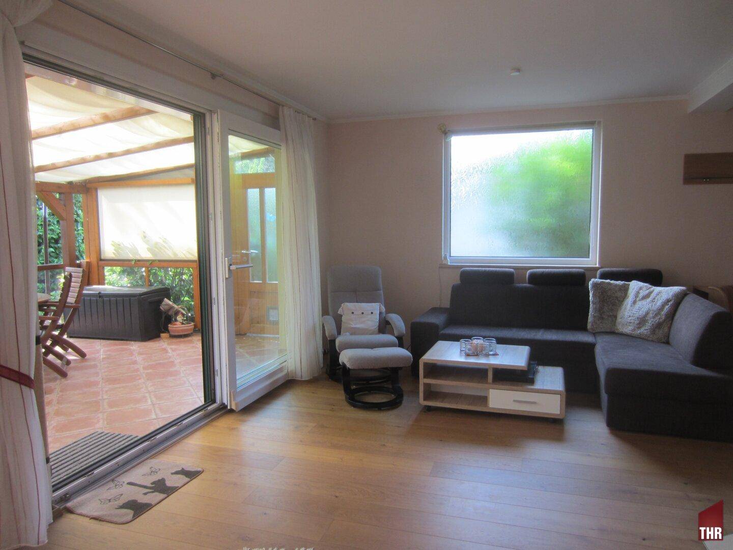 Geräumiges Wohnzimmer mit Sofa, Couchtisch und großen Schiebetüren zur Terrasse.