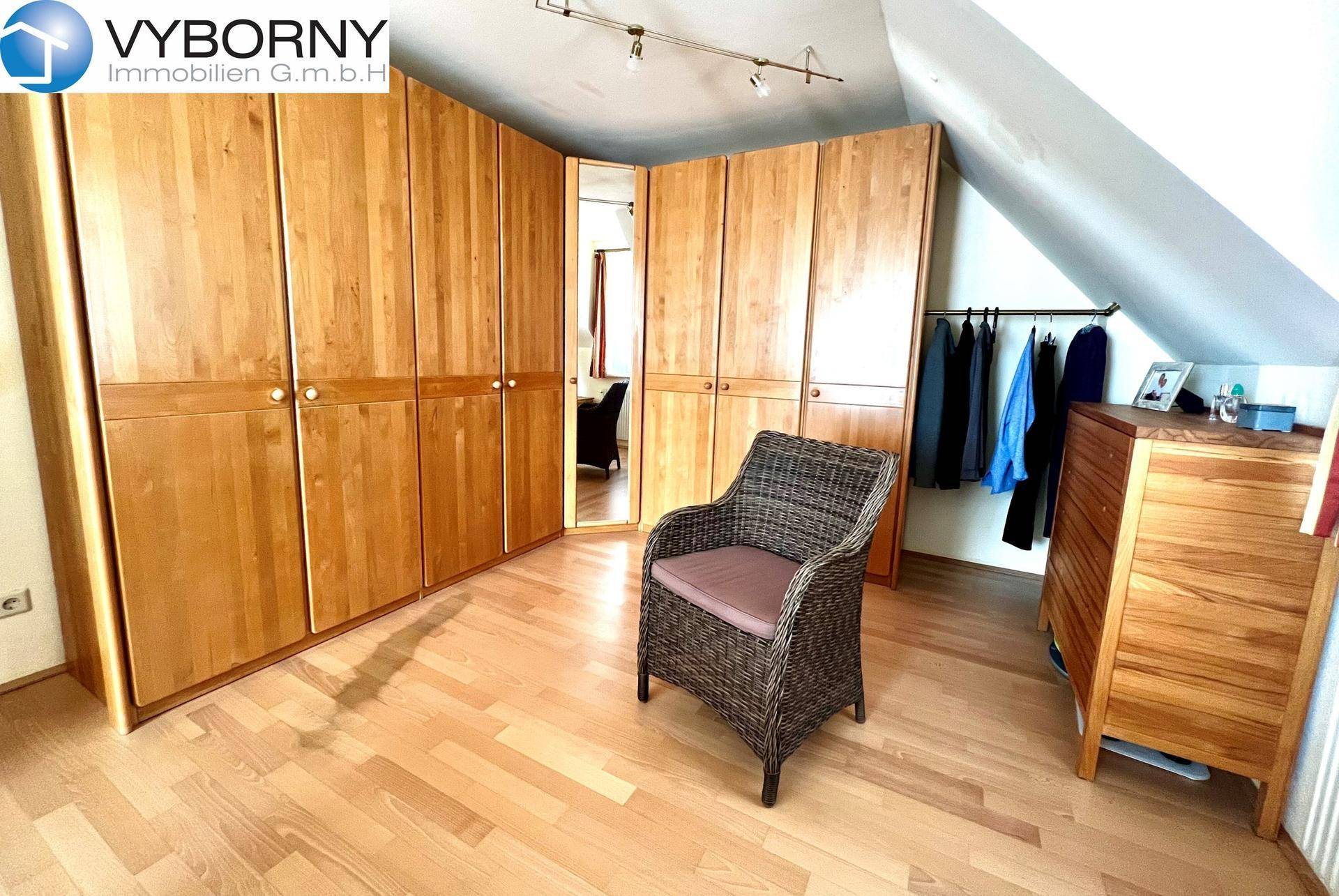 Schlafzimmer mit großen Holzschränken, Holzboden und Dachschrägen.