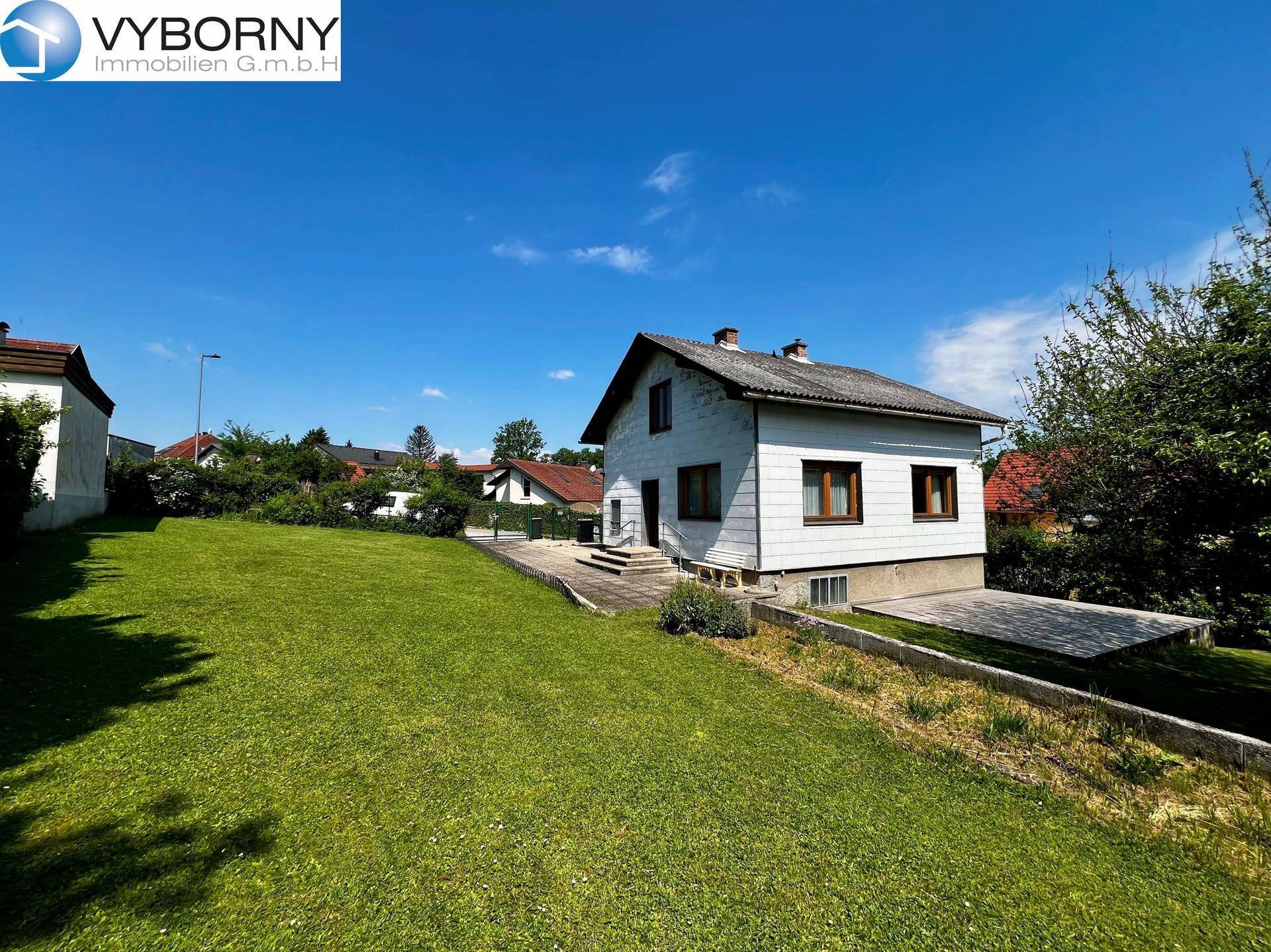 Seitenansicht des Hauses mit weitläufigem Garten, Zufahrt und Blick auf die Nachbarschaft.