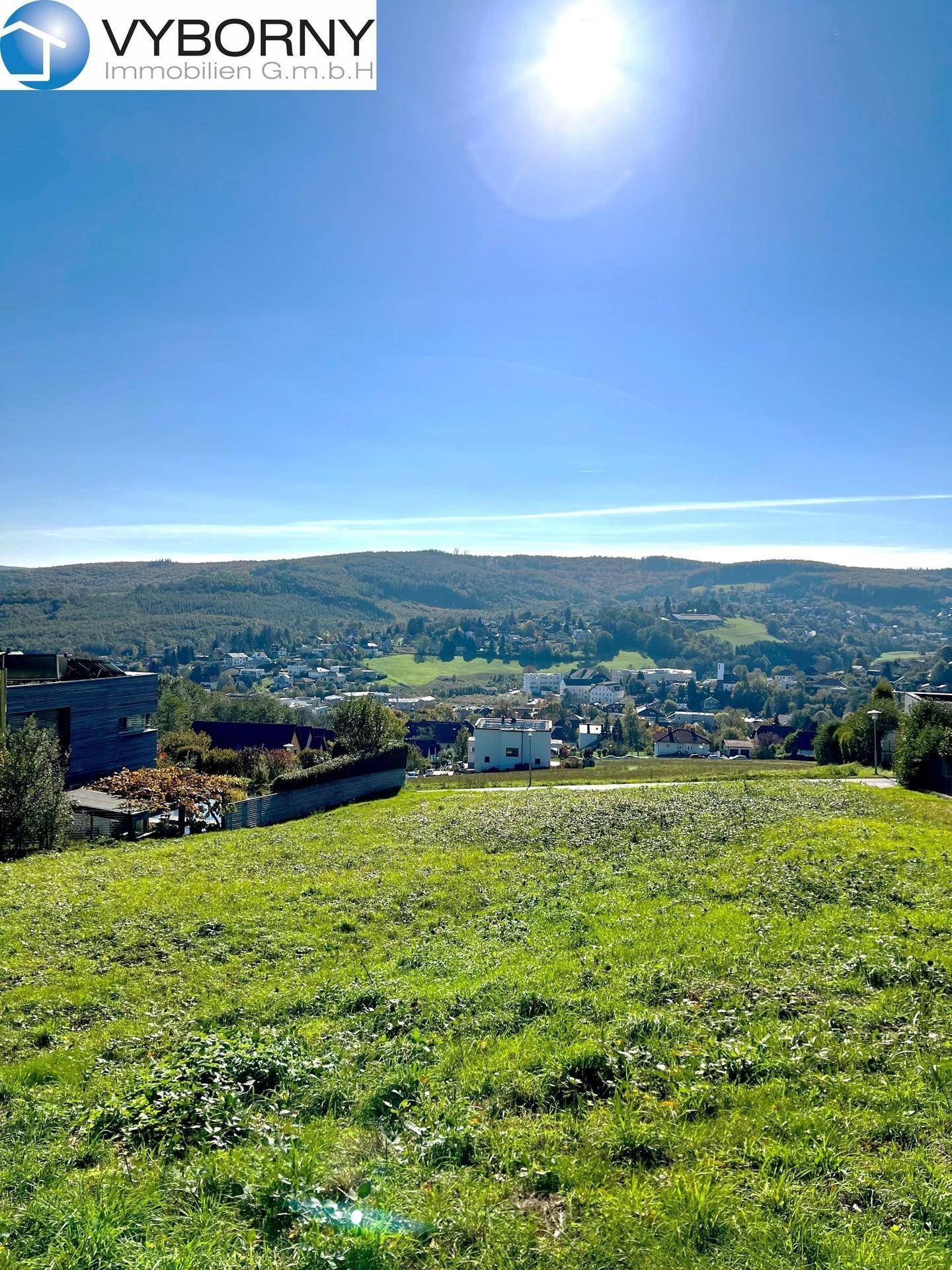 Weitläufiges Grundstück mit Panoramablick auf die umliegende Hügellandschaft und eine Ortschaft.