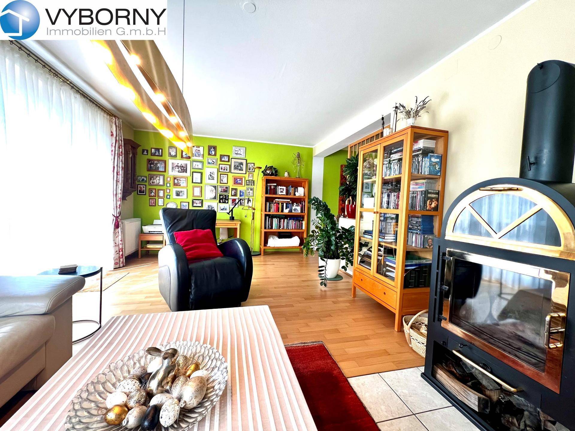 Wohnzimmer mit Kaminofen, Holzboden und einer auffälligen grünen Akzentwand.