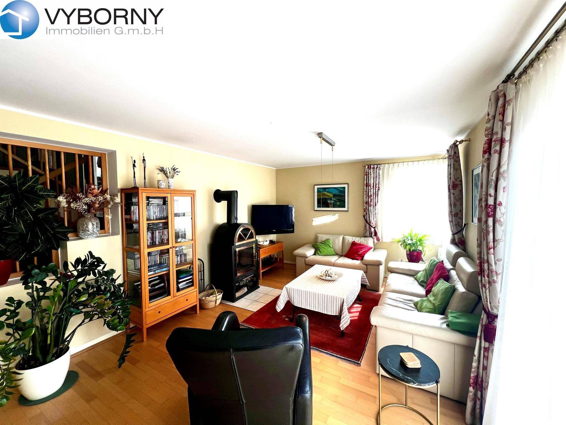 Gemütliches Wohnzimmer mit Holzboden, Kaminofen und beigen Sofas.