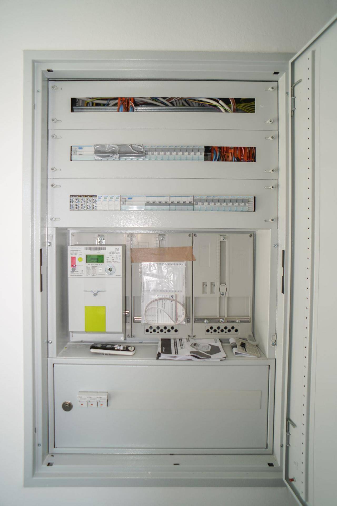 Offener Sicherungskasten mit Stromzähler und verschiedenen elektrischen Installationen.