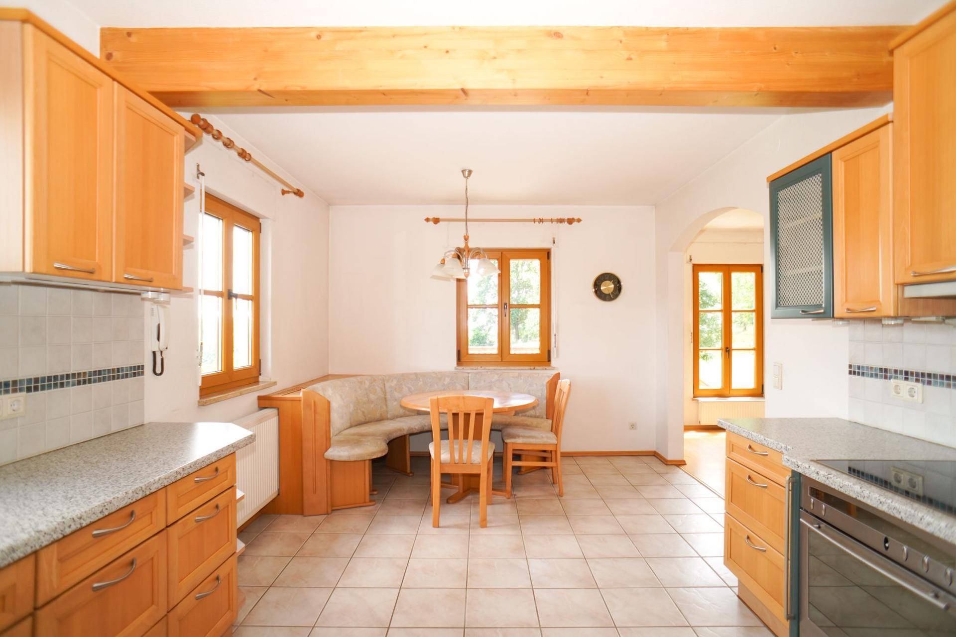 Funktionale Küche mit Holzschränken, gefliestem Boden und integriertem Essbereich mit Eckbank.