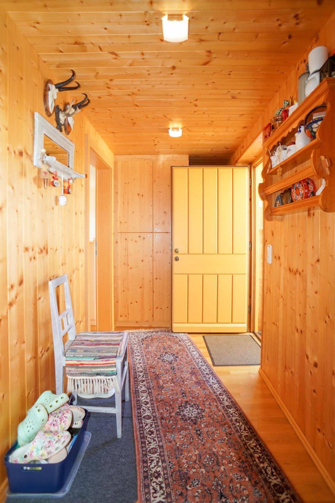 Gemütlicher Flur mit Holzvertäfelung, Teppichläufer und traditioneller alpiner Dekoration.