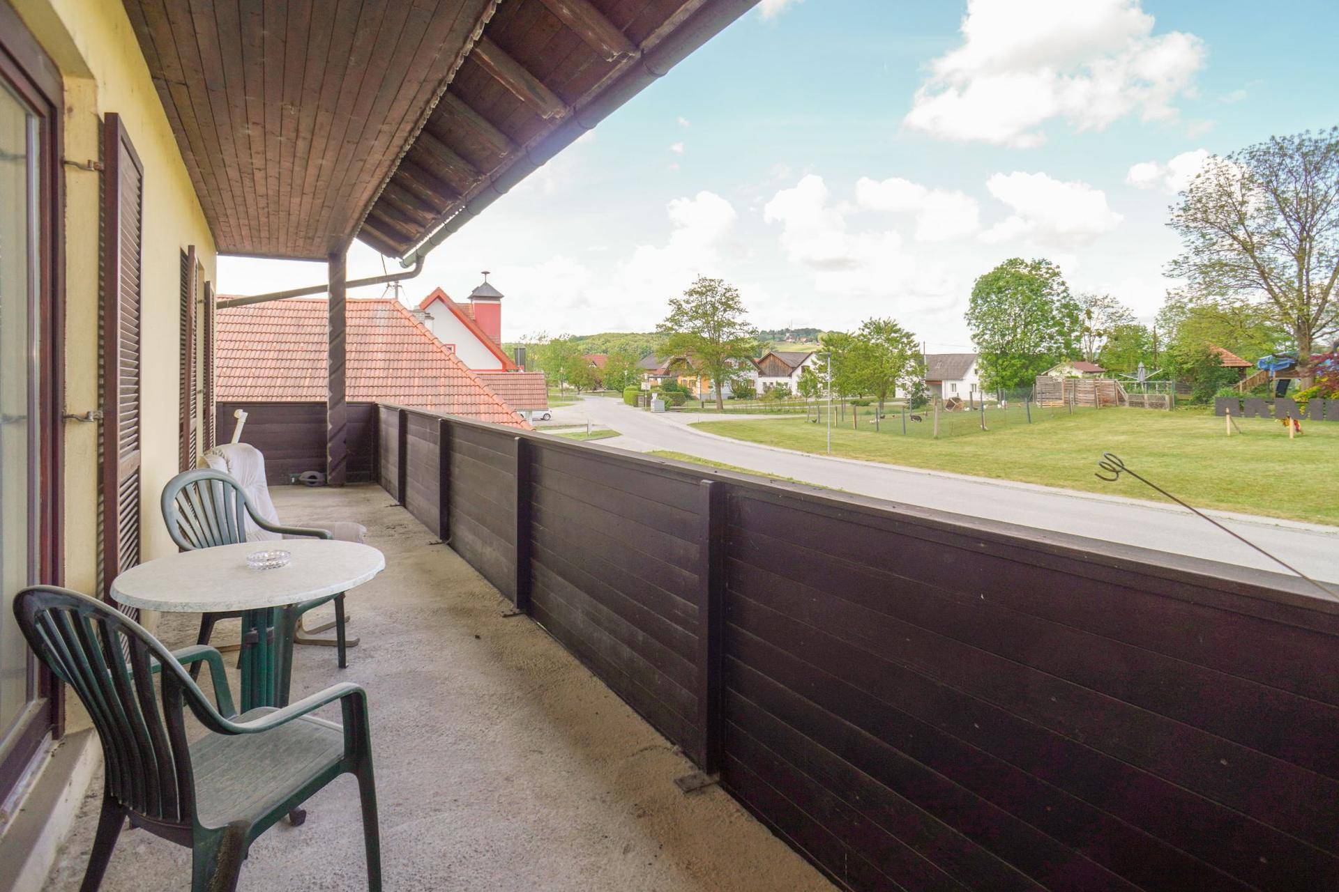 Balkon mit Holzboden und Sitzgelegenheiten, bietet einen weiten Blick auf die ländliche Umgebung.