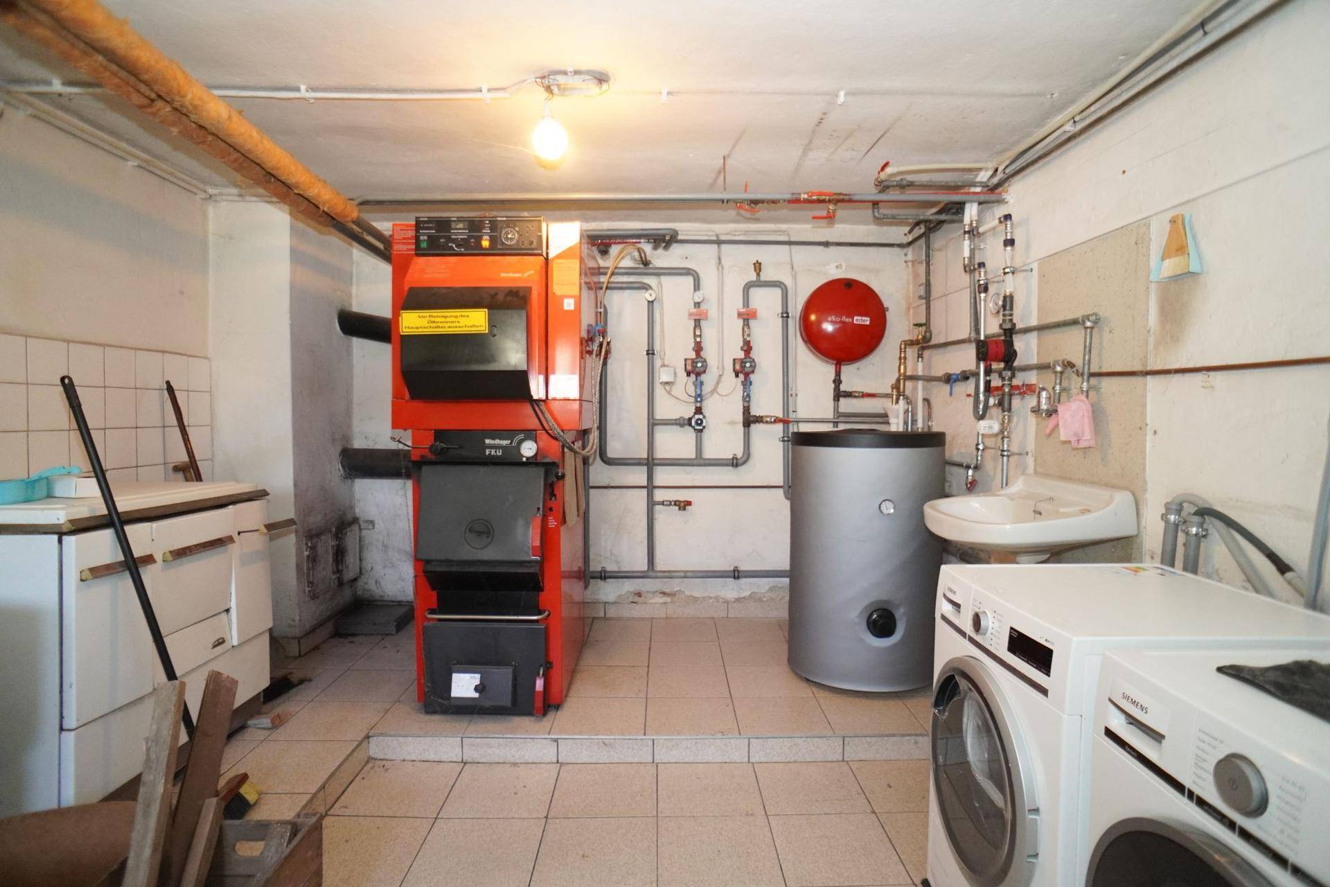 Hauswirtschaftsraum im Keller mit Heizungsanlage, Warmwasserspeicher und Waschmaschinen.