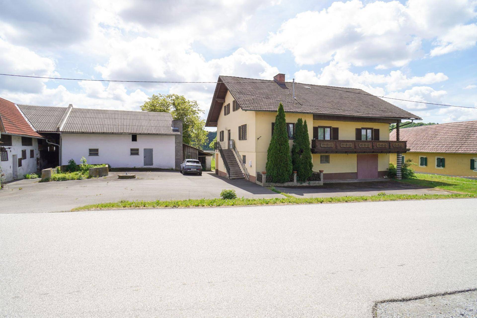 Gesamtansicht des ländlichen Anwesens mit Wohnhaus, Nebengebäuden und Zufahrt von der Straße.