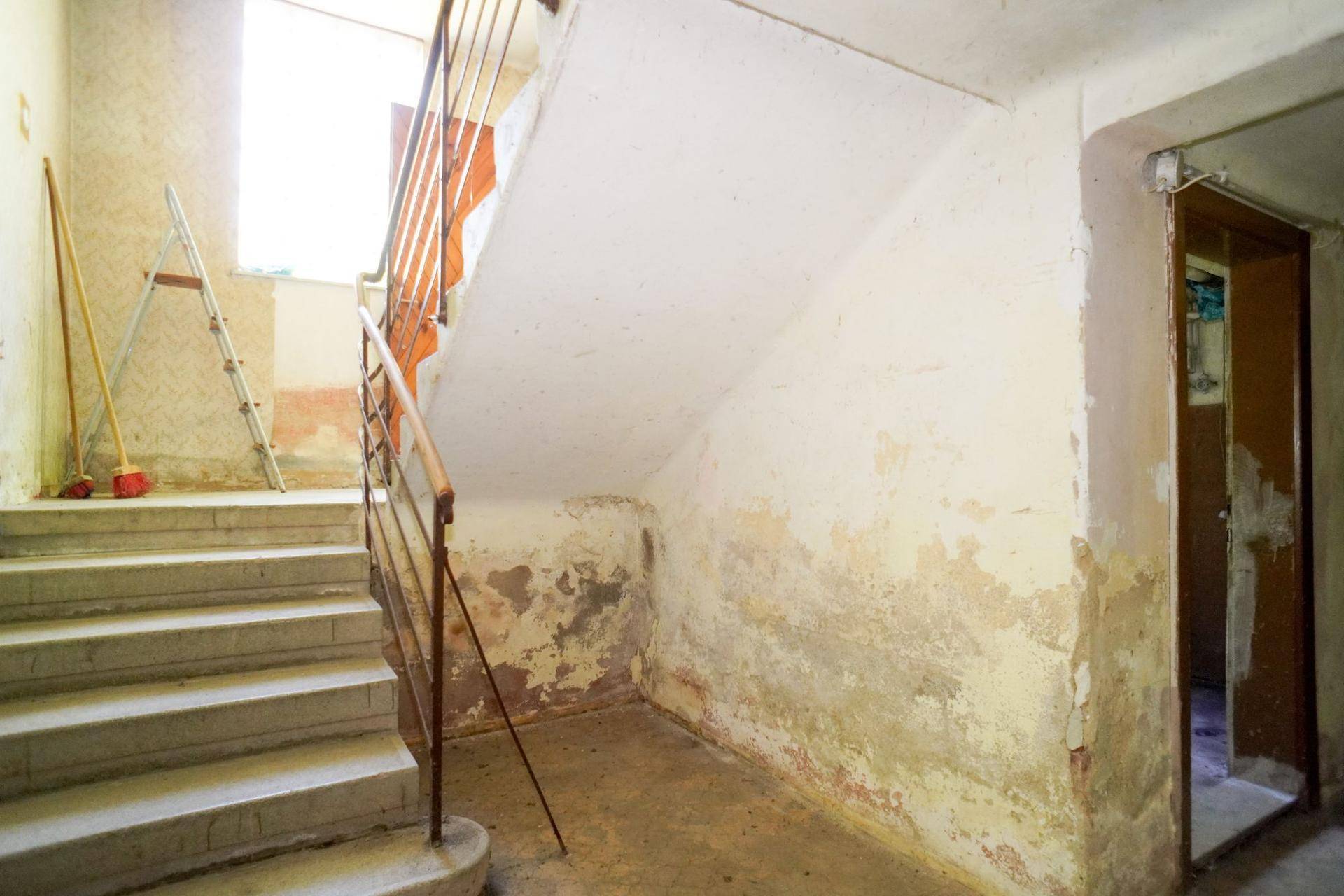 Treppenhaus mit Renovierungsbedarf, sichtbaren Abnutzungsspuren und Werkzeugen.