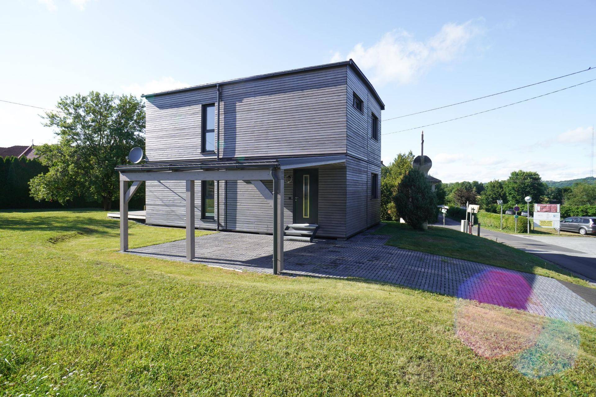 Vorderansicht des modernen Hauses mit Carport, gepflasterter Auffahrt und großem Vorgarten.