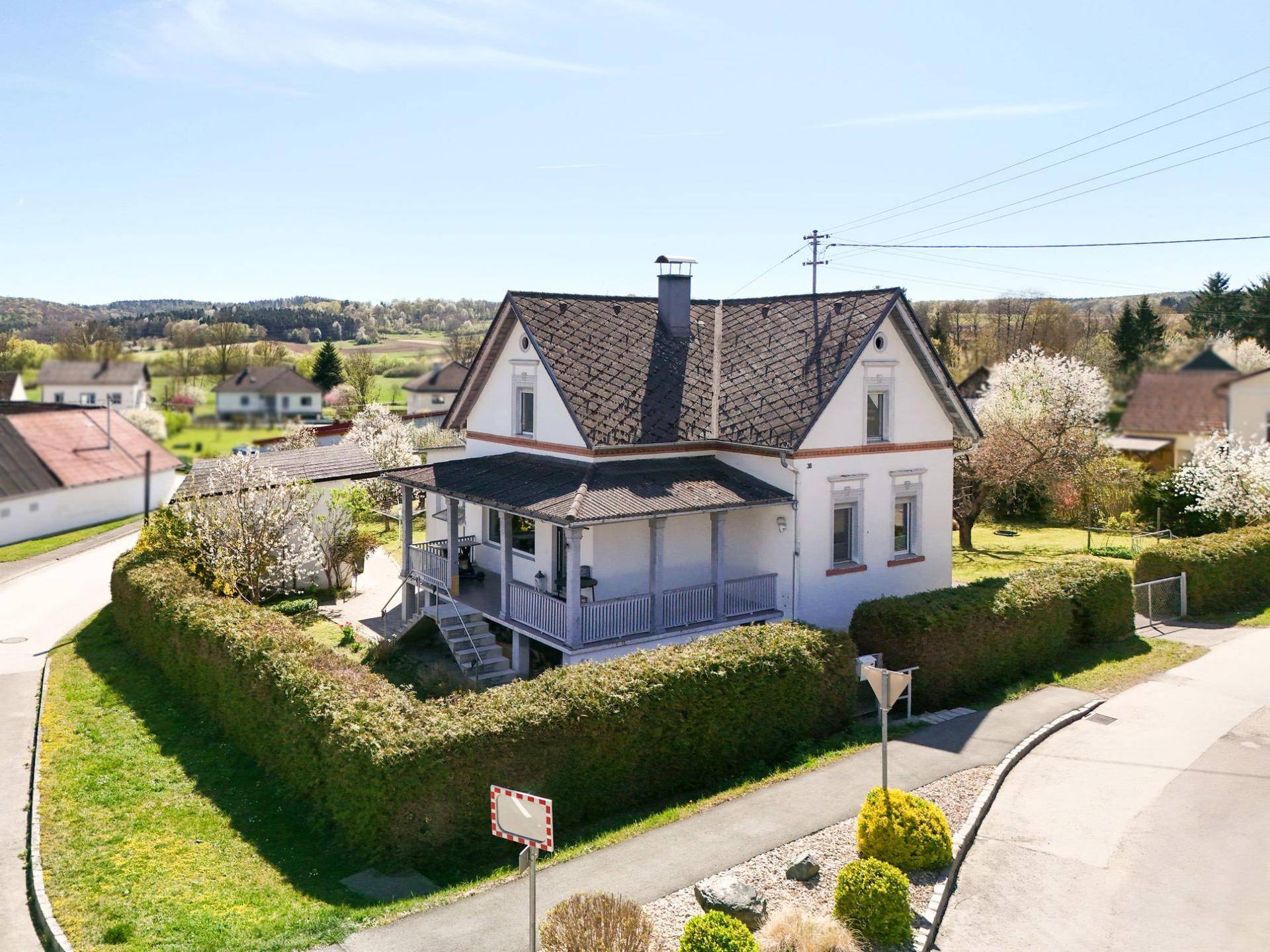 Luftaufnahme des Hauses auf einem Eckgrundstück mit gepflegten Hecken und weitem Blick in die Landschaft.