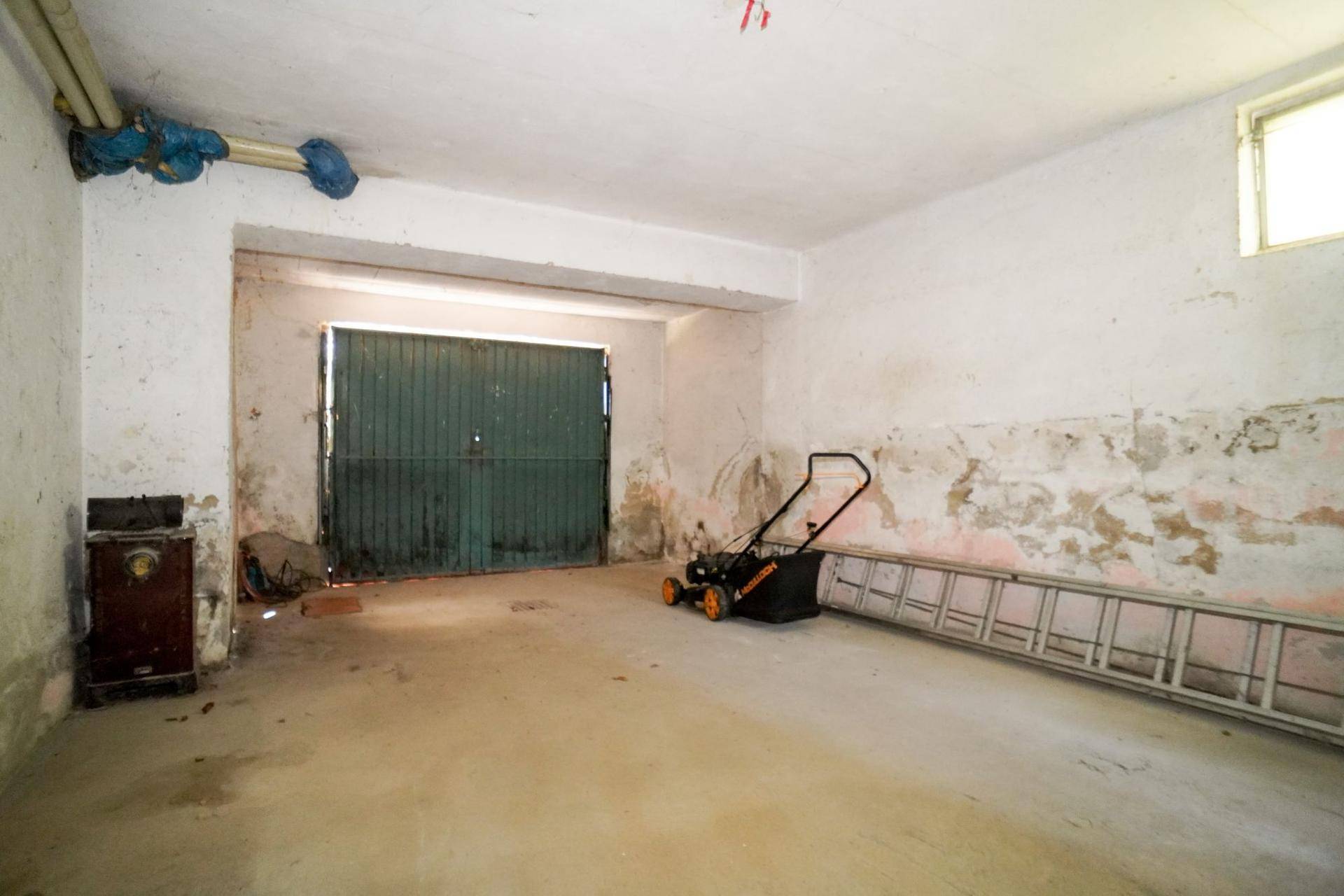 Geräumige Garage im Untergeschoss mit alten Toren und Lagerfläche.