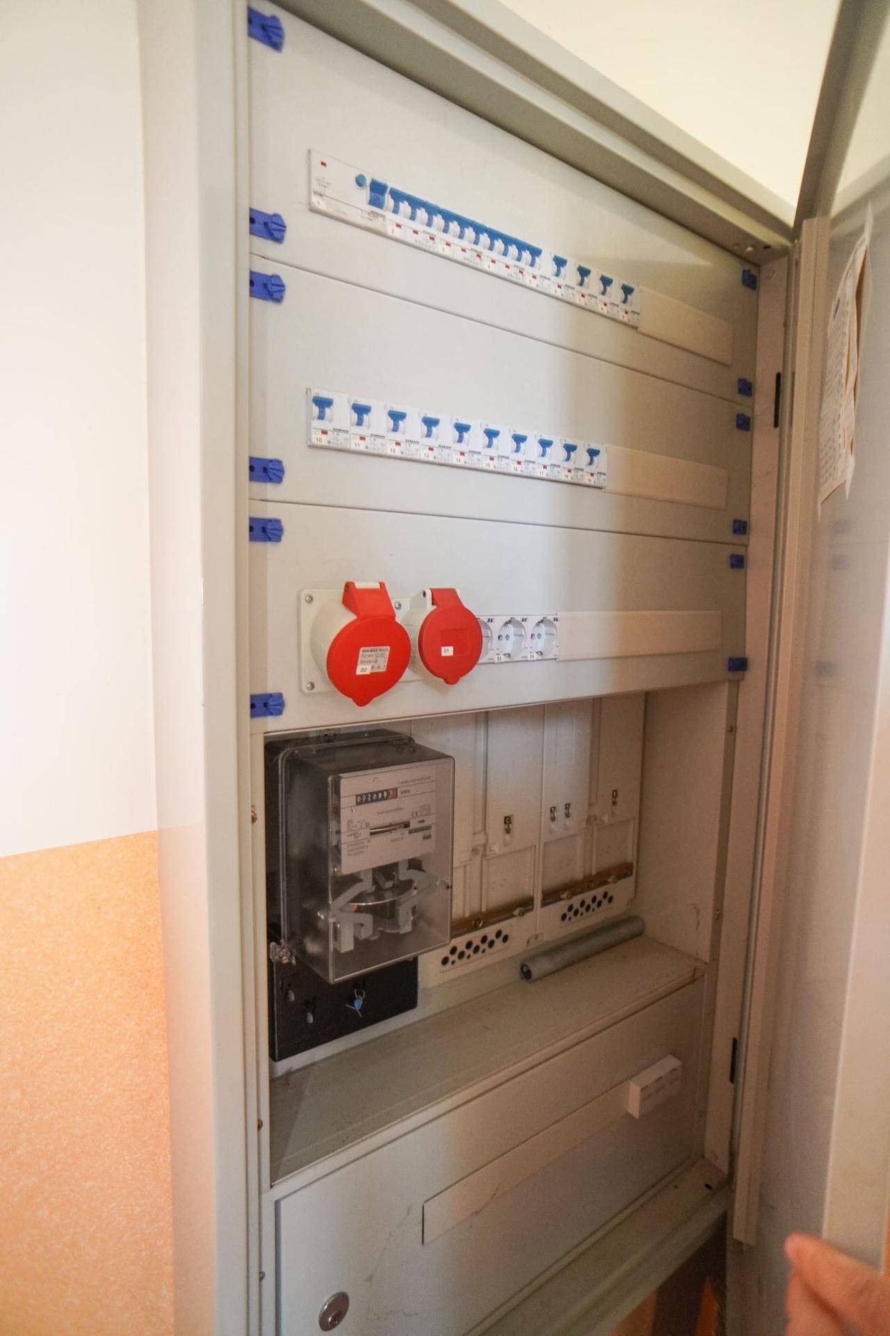 Elektrischer Verteilerkasten mit Sicherungen und Zähler in einem Innenraum.