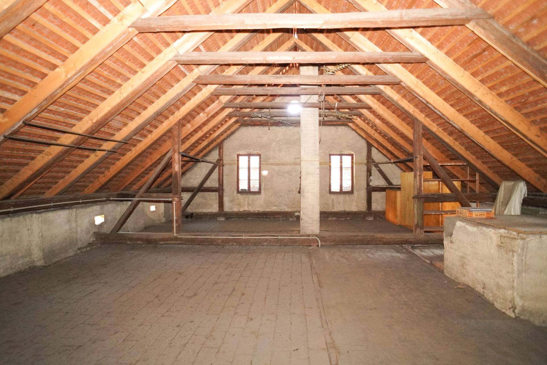 Geräumiger Dachboden mit sichtbarer Holzkonstruktion und zwei Fenstern, bietet Ausbaupotenzial.