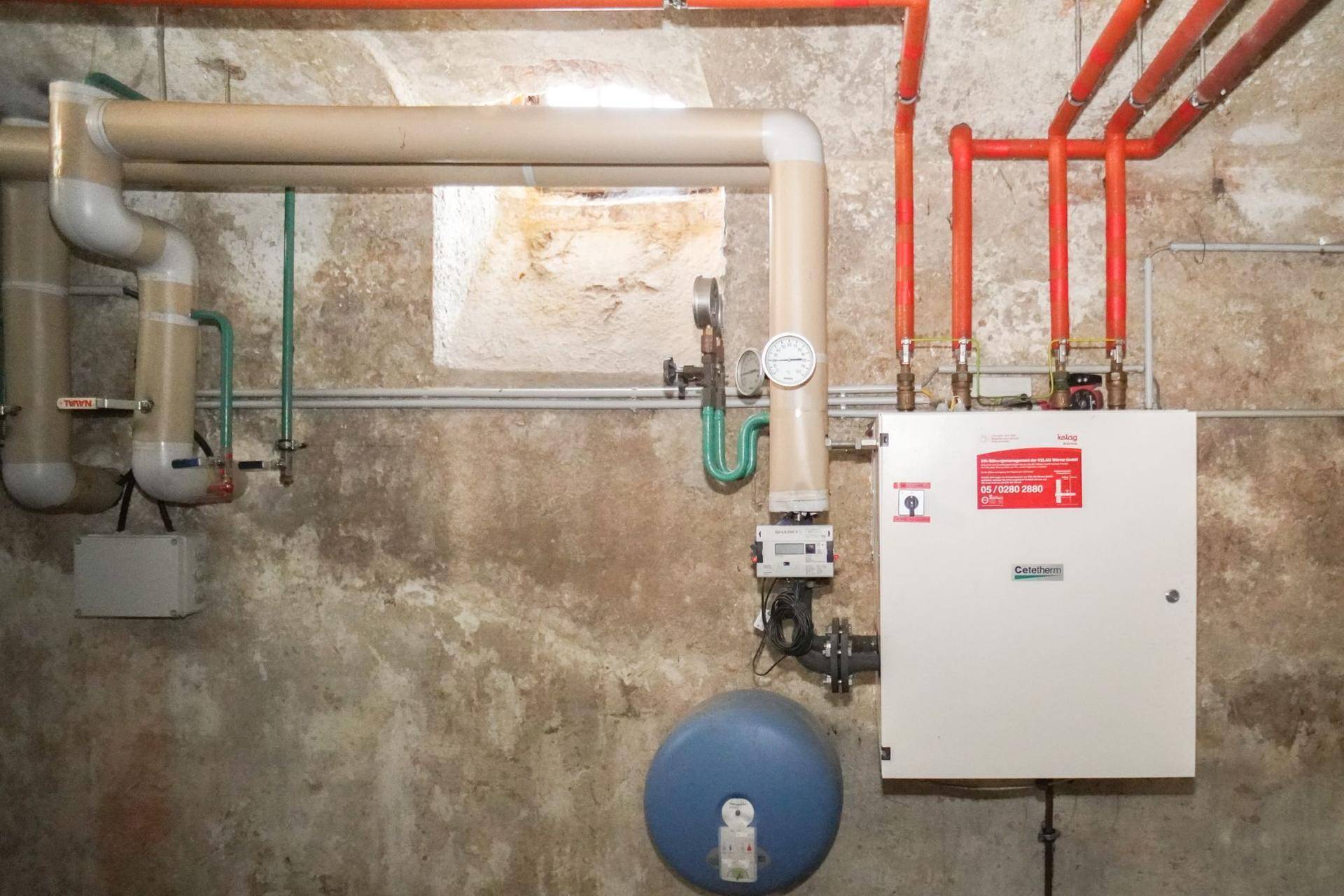 Detailansicht der Heizungsanlage im Keller mit verschiedenen Rohren und Ventilen.