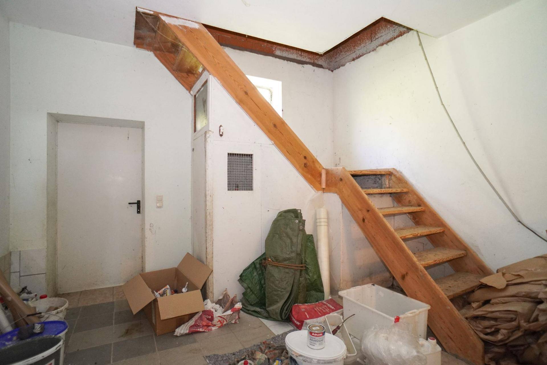 Eingangsbereich mit einfacher Holztreppe und sichtbaren Bauarbeiten, rustikaler Charme.