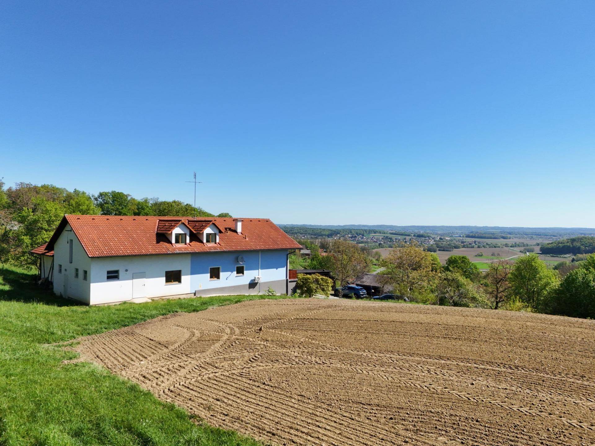 Ländliches Haus mit weitem Blick über Felder und grüne Hügel, idyllische Umgebung.