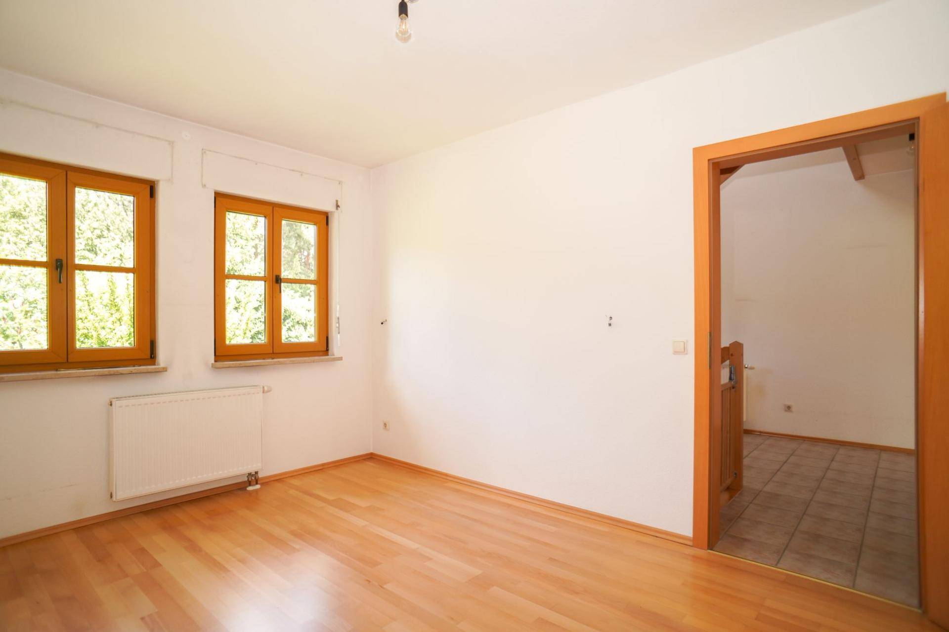 Geräumiges Schlafzimmer mit Holzboden und Zugang zu einem angrenzenden Flur, hell und freundlich.
