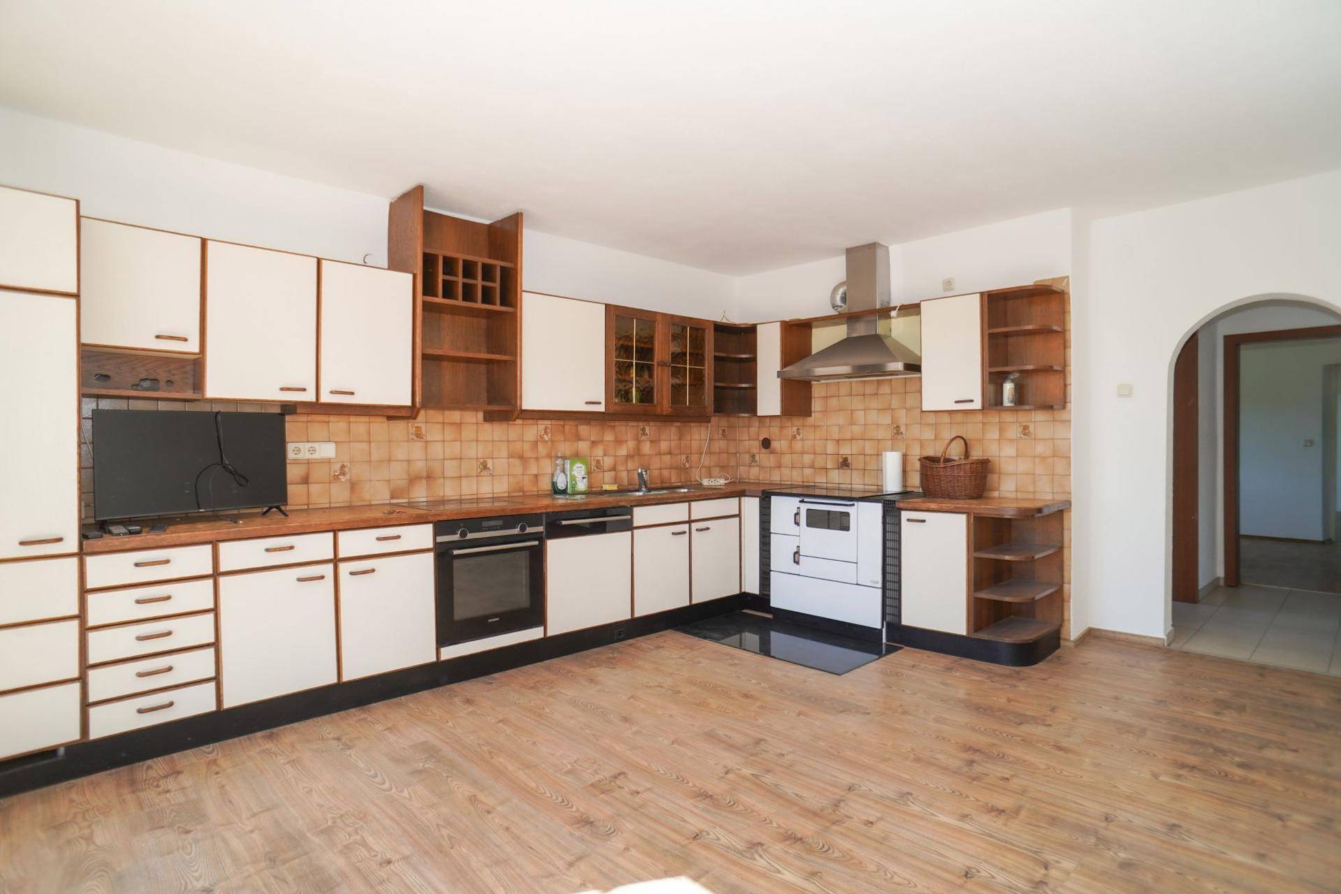 Funktionale Küche mit Holz- und weißen Schränken, Fliesenrückwand und Herd.