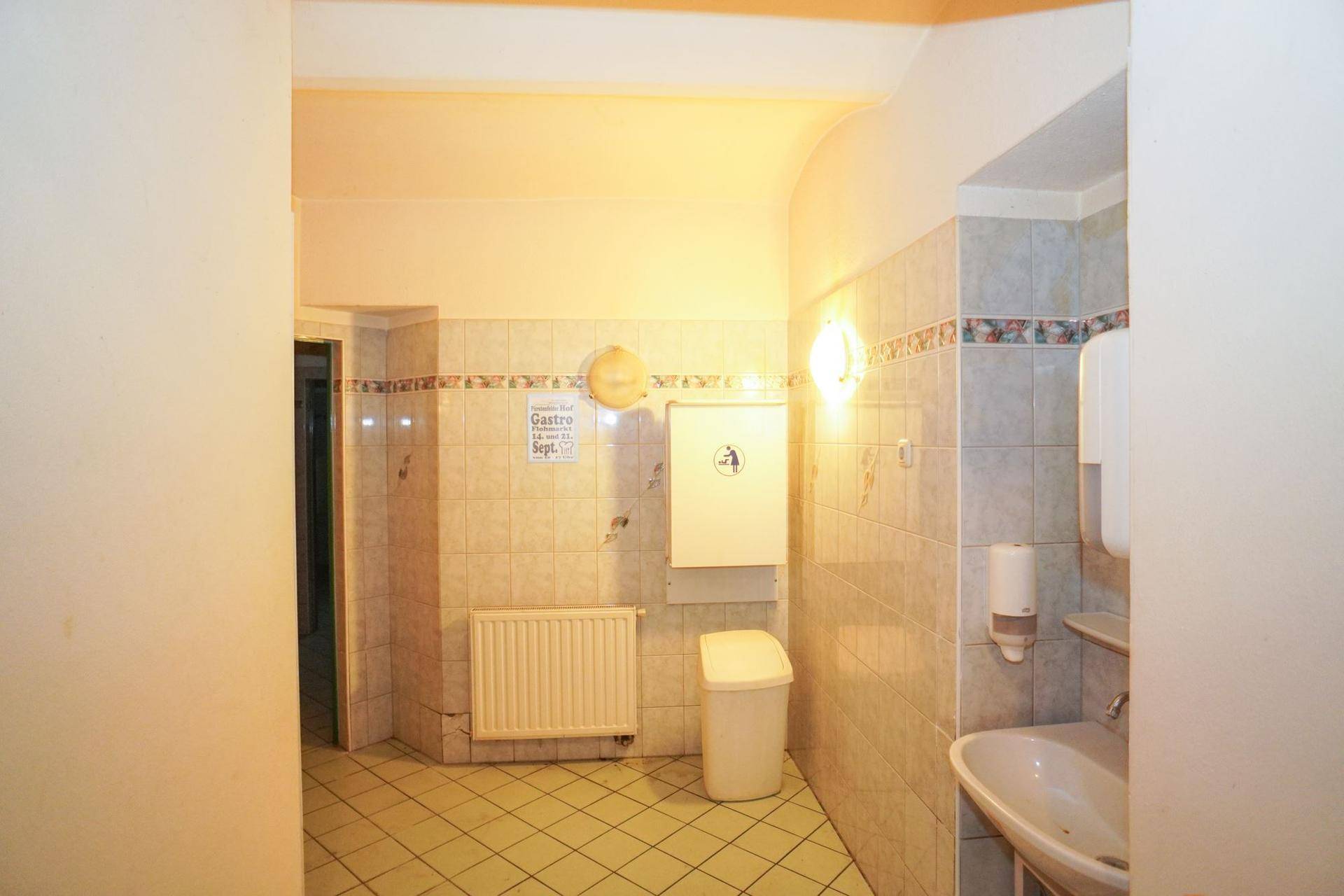 Toilettenbereich mit Waschbecken, Heizkörper und gefliesten Wänden im traditionellen Stil.