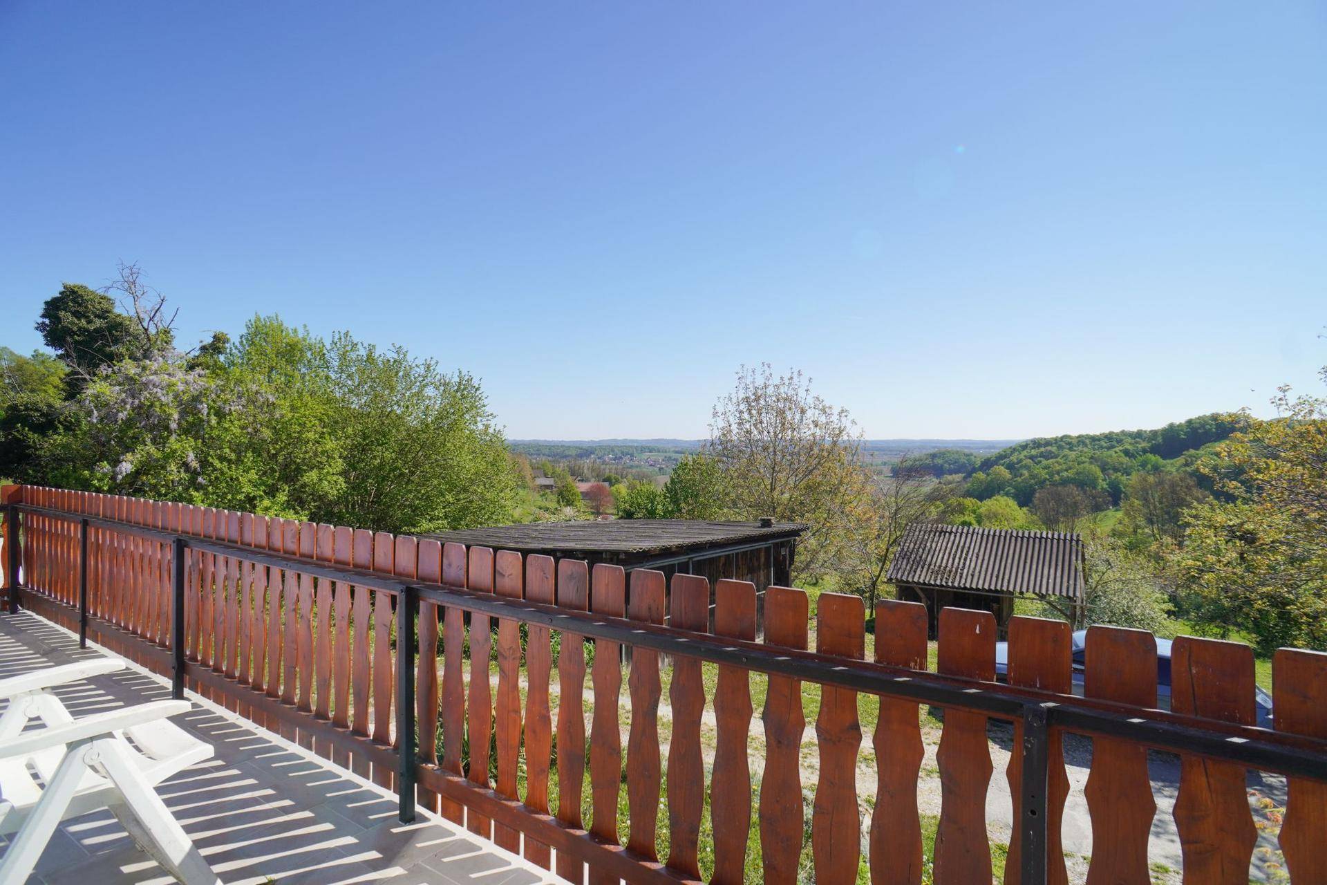 Balkon mit Holzzaun und weitem Blick über die grüne Hügellandschaft.