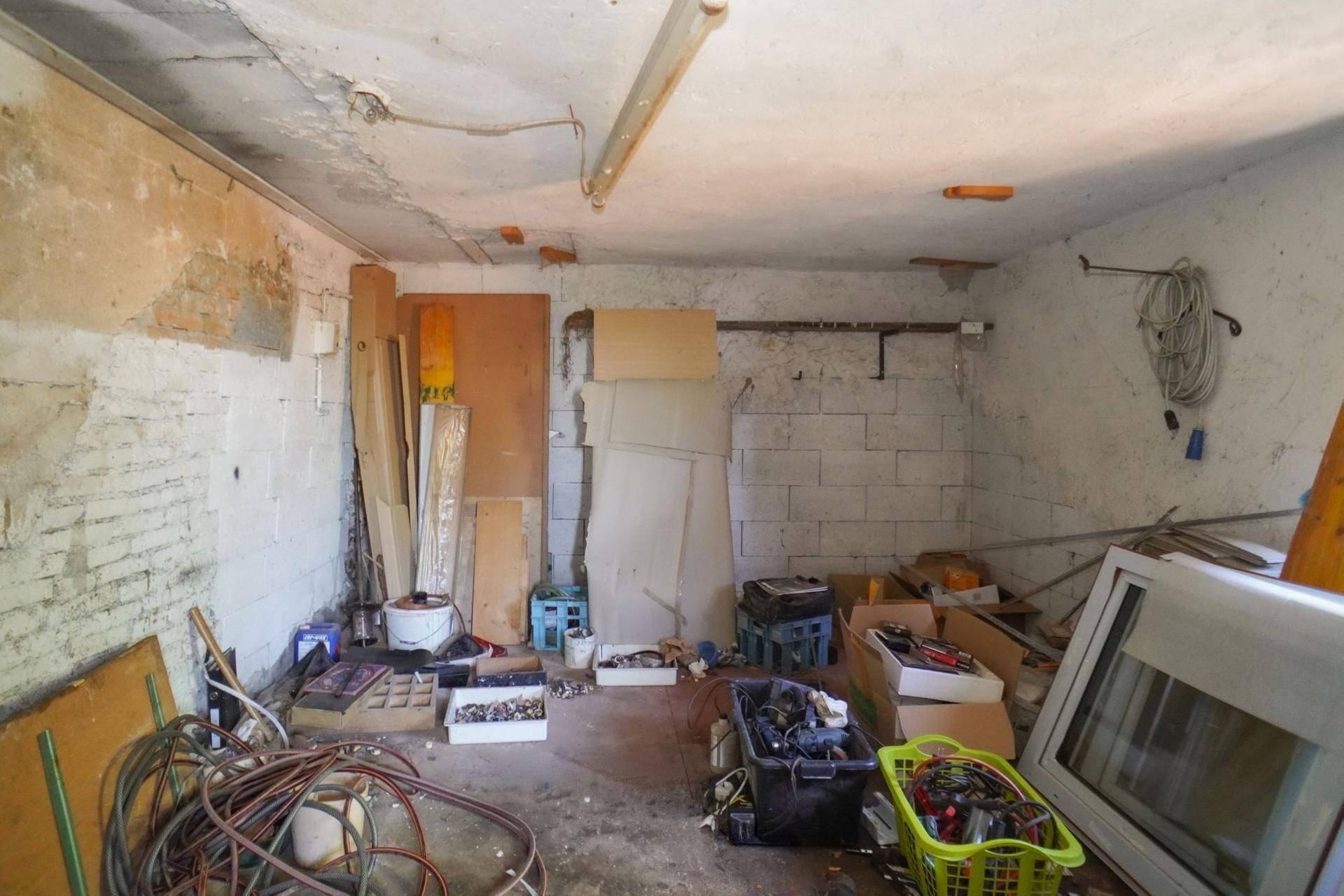 Unaufgeräumter Kellerraum mit verschiedenen Materialien und Werkzeugen, viel Stauraum.