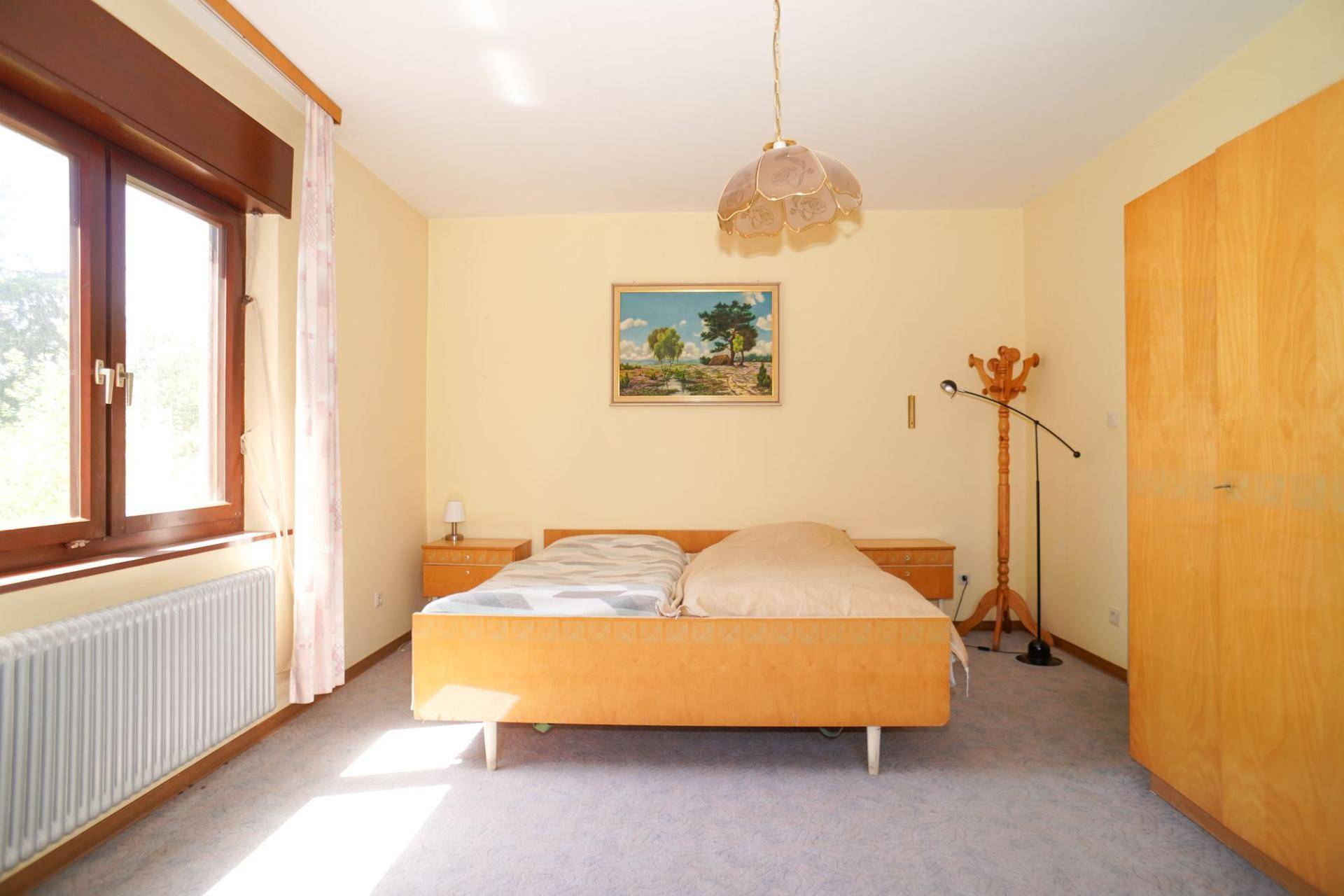 Gemütliches Schlafzimmer mit Doppelbett, Teppichboden und viel Tageslicht.