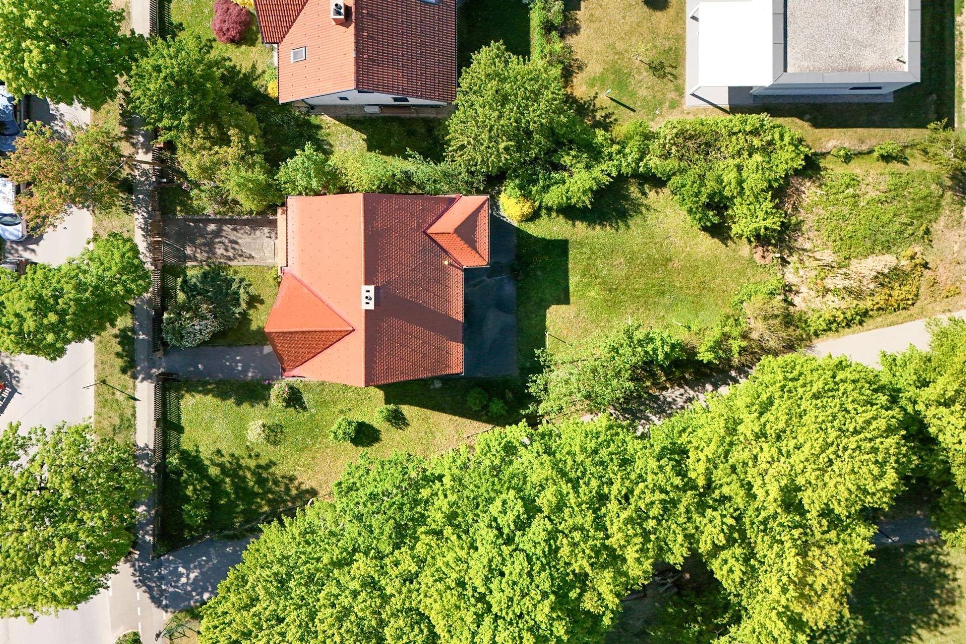 Luftaufnahme des Hauses mit rotem Dach, großem Grundstück und umliegenden Bäumen.