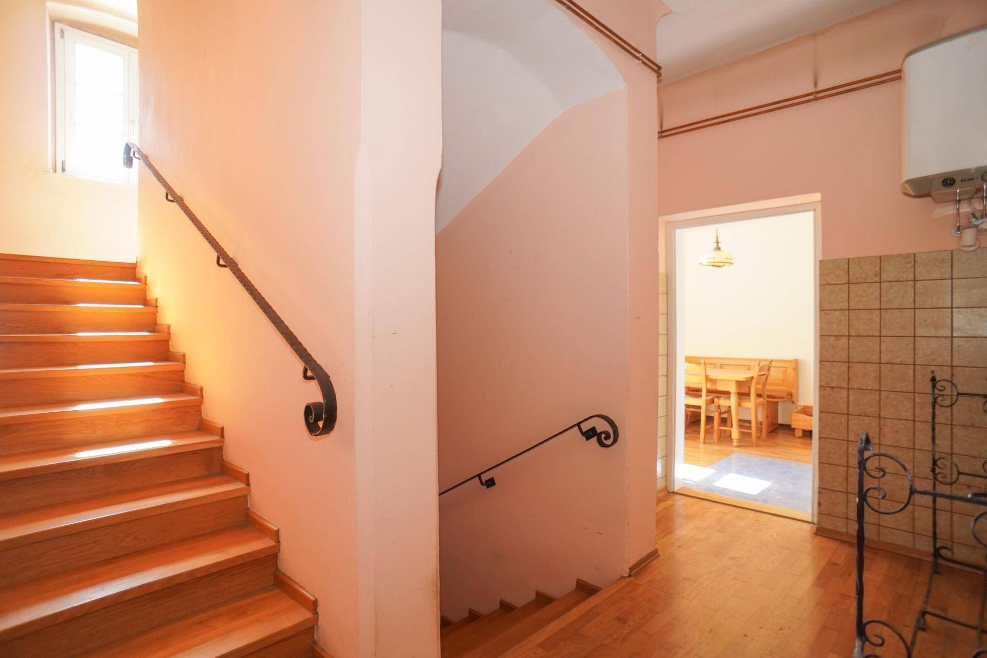 Heller Flur mit Holztreppe und schmiedeeisernem Geländer, führt zu weiteren Räumen.