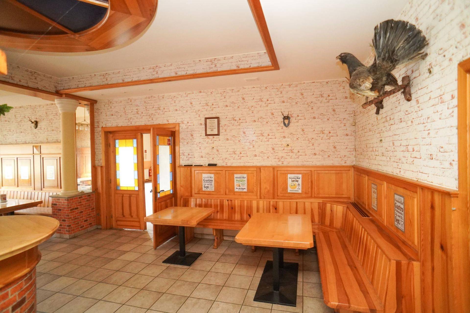 Gemütlicher Essbereich mit Holzbänken, Tischen und rustikalen Wandverkleidungen.