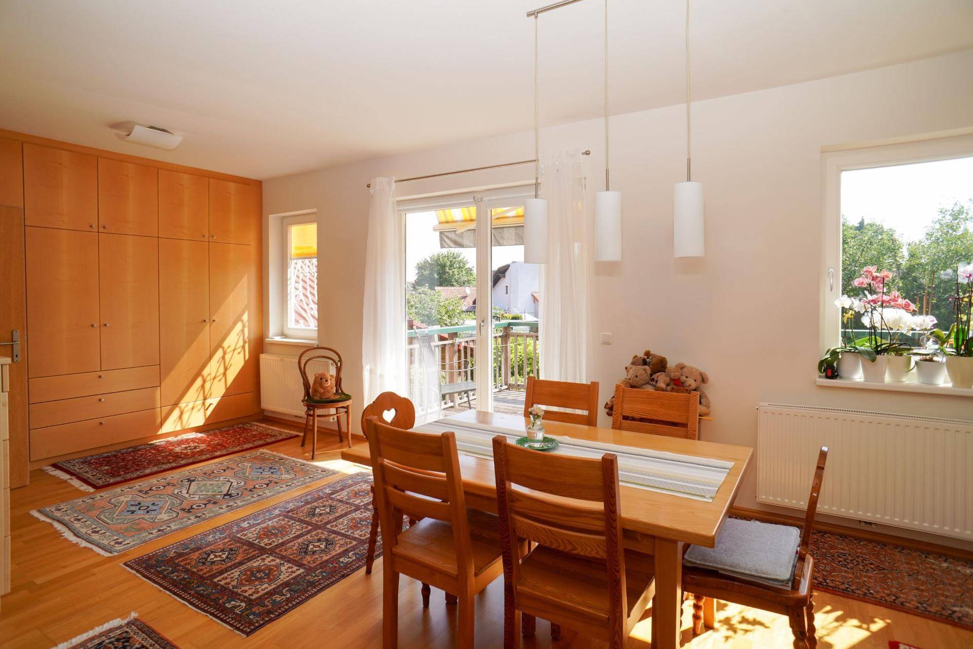 Heller Essbereich mit Holztisch, Einbauschränken und Zugang zu einem sonnigen Balkon.