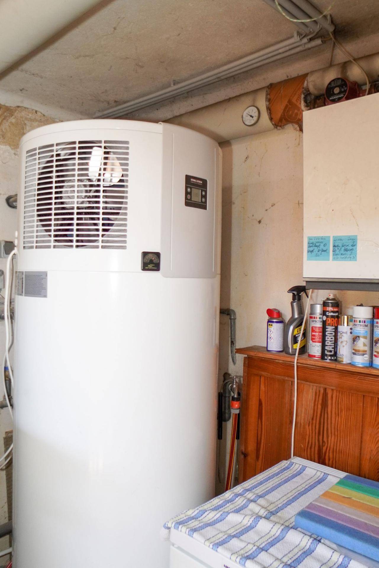Technikraum im Keller mit einem modernen Warmwasserspeicher und Regalen für Lagerung.