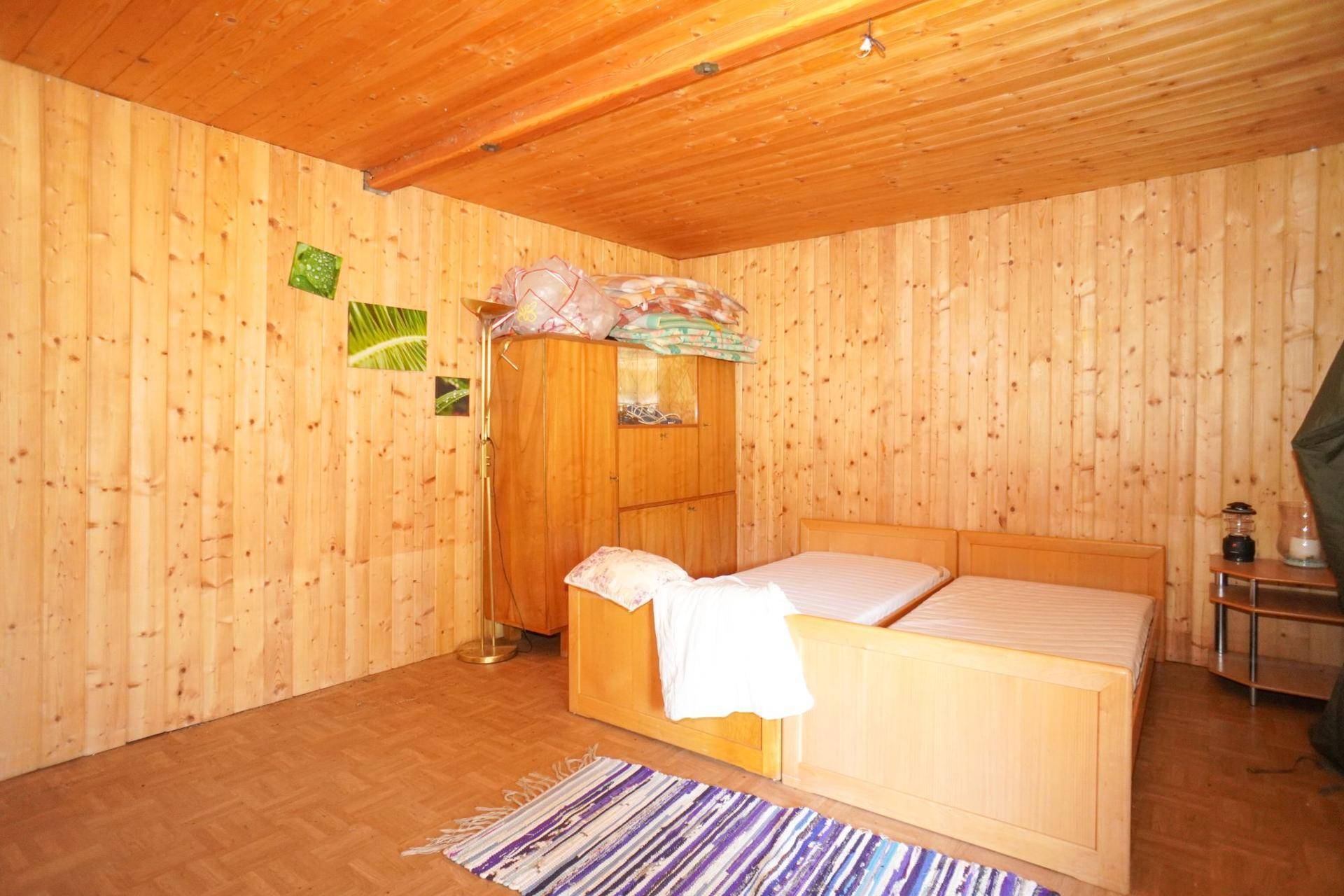 Schlafzimmer mit holzvertäfelten Wänden und Decke, ausgestattet mit zwei Einzelbetten.