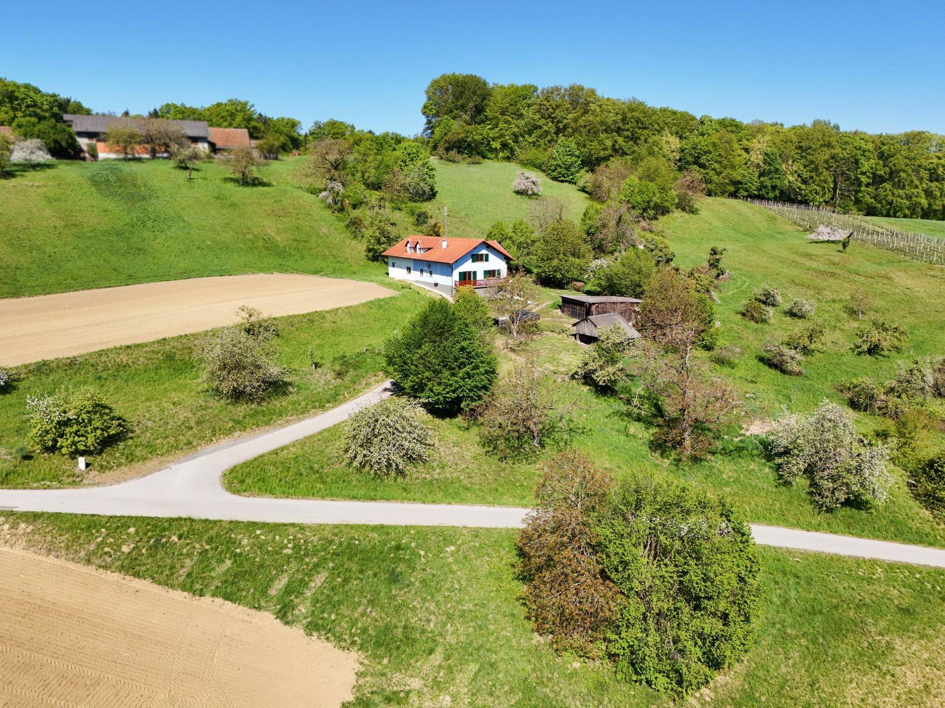 Panoramablick aus der Vogelperspektive auf ein Haus inmitten von Feldern und Wäldern.