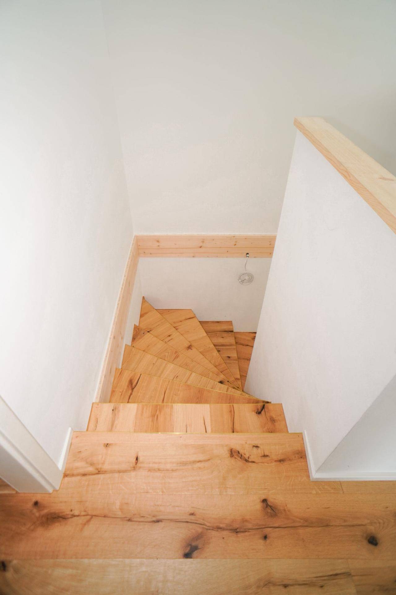 Holztreppe mit offenen Stufen, die die verschiedenen Ebenen des Hauses verbindet.