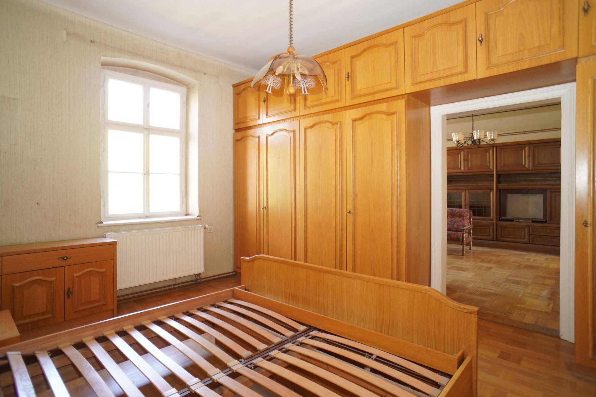 Schlafzimmer mit großem Einbauschrank und Holzbett, bietet direkten Zugang zu einem weiteren Raum.