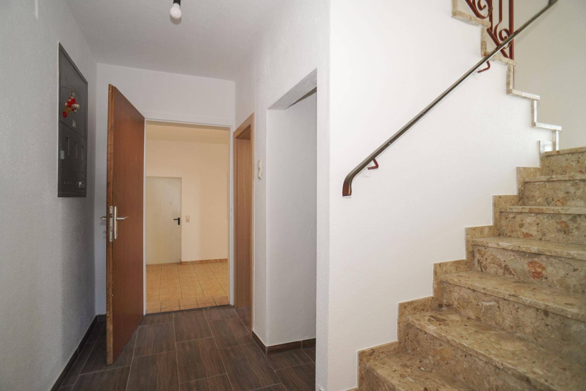 Eingangsbereich mit Fliesenboden und Steintreppe, die zu den oberen Etagen führt.