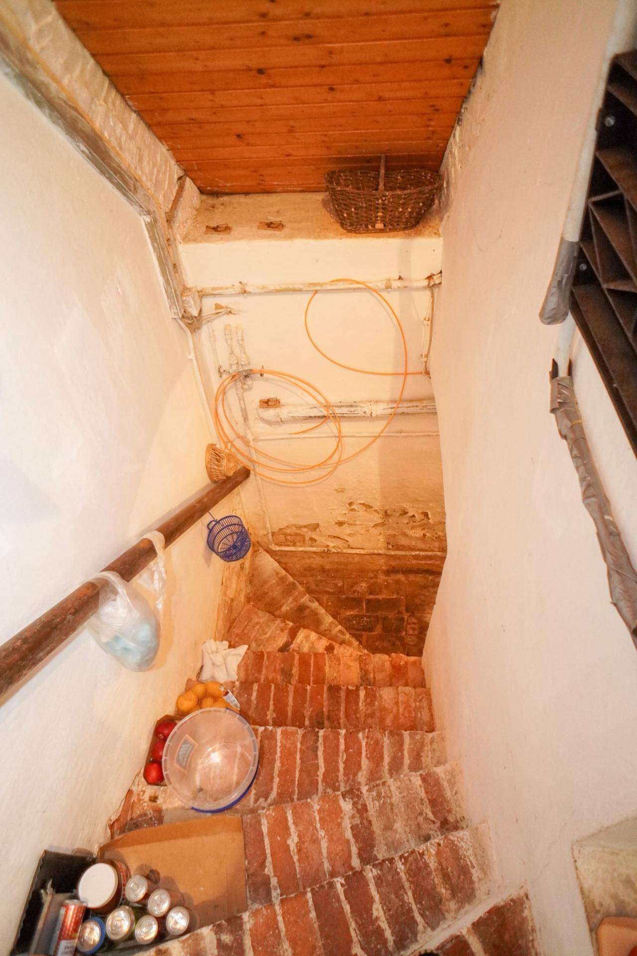 Rustikale Kellertreppe aus Ziegeln, die in einen Lagerbereich mit unfertigen Wänden führt.
