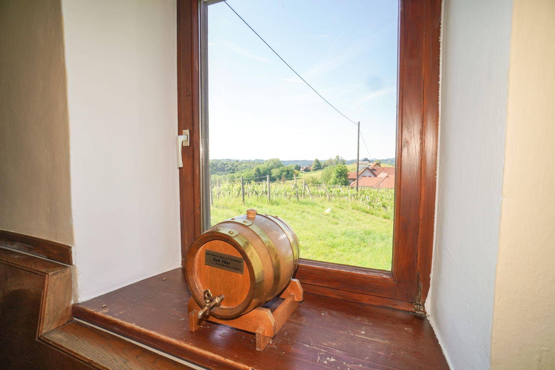 Fenster mit Holzeinfassung und einem kleinen Weinfass, bietet einen Blick auf die Weinberge.