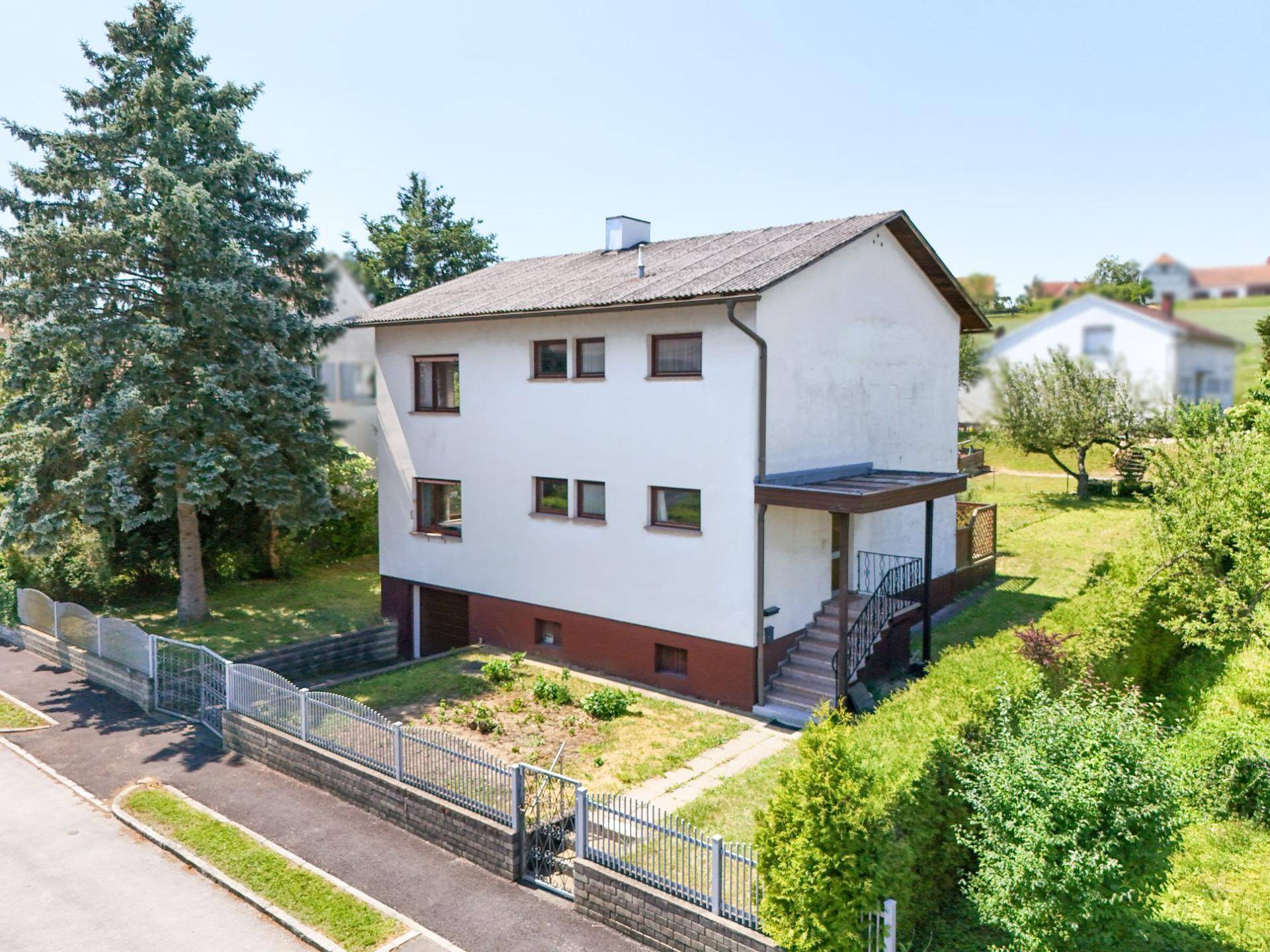Vorderansicht des Einfamilienhauses mit Gartenbereich und Zufahrt in ländlicher Umgebung.
