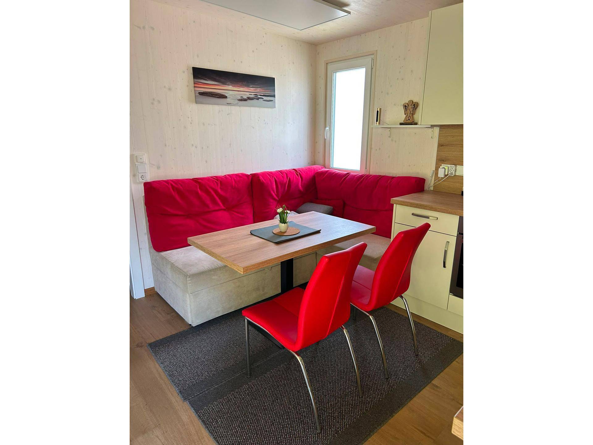 Gemütliche Essecke in der Küche mit roter Eckbank, Holztisch und modernen Stühlen.