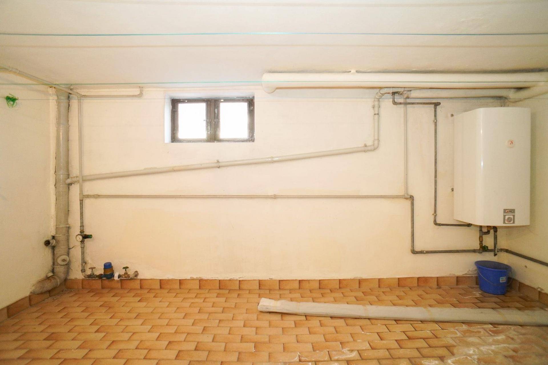 Heller Kellerraum mit Terrakottafliesen, Warmwasserbereiter und sichtbaren Installationen, gut nutzbar.