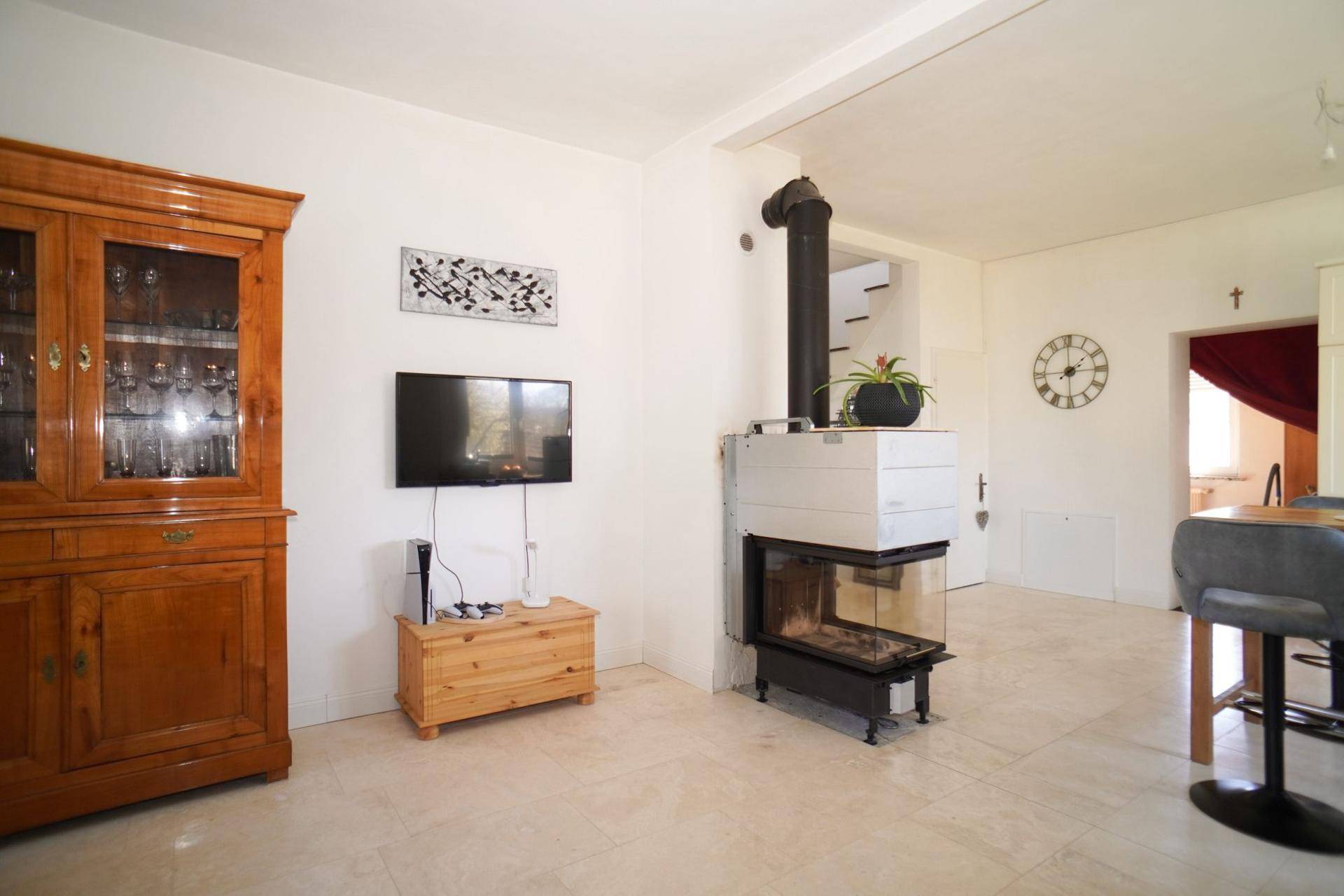 Wohnbereich mit modernem Kaminofen, Holzanrichte und Wandfernseher, offen zur Küche.
