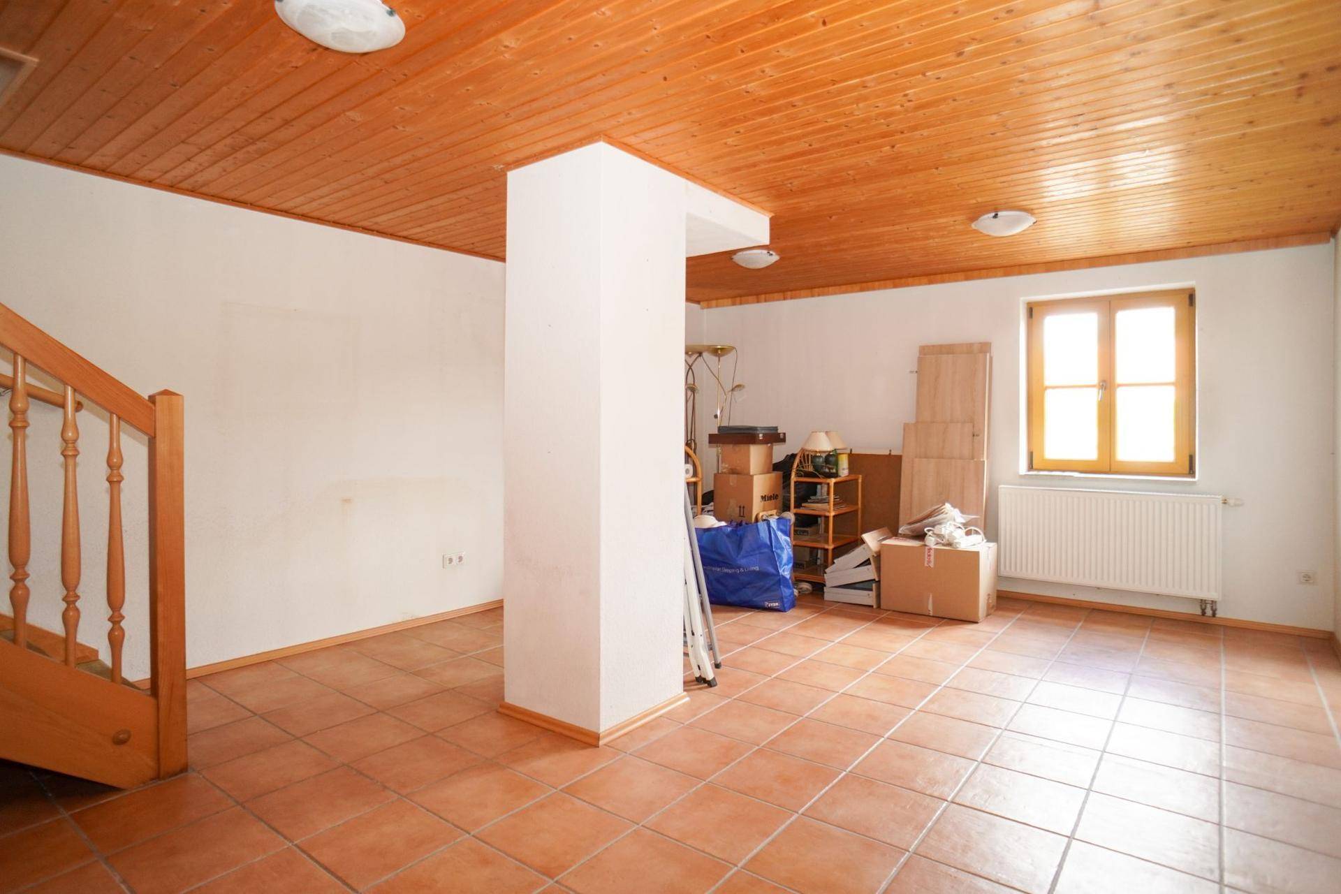 Geräumiger Kellerraum mit Holzdecke, Fliesenboden und Tageslichtfenster, ideal als Abstellfläche.