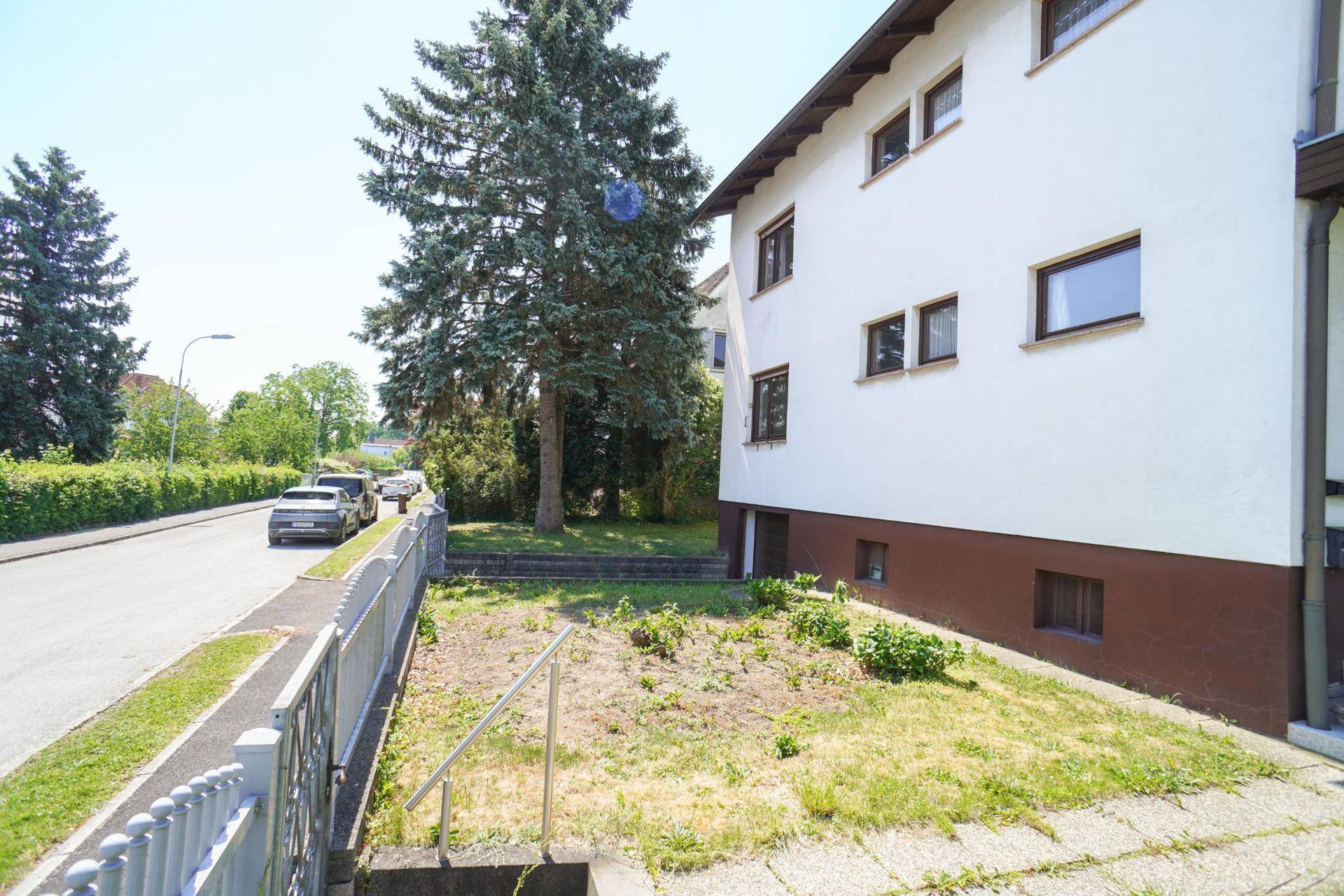 Seitenansicht des Hauses mit kleinem Vorgarten, Zaun und Blick auf die ruhige Anliegerstraße.