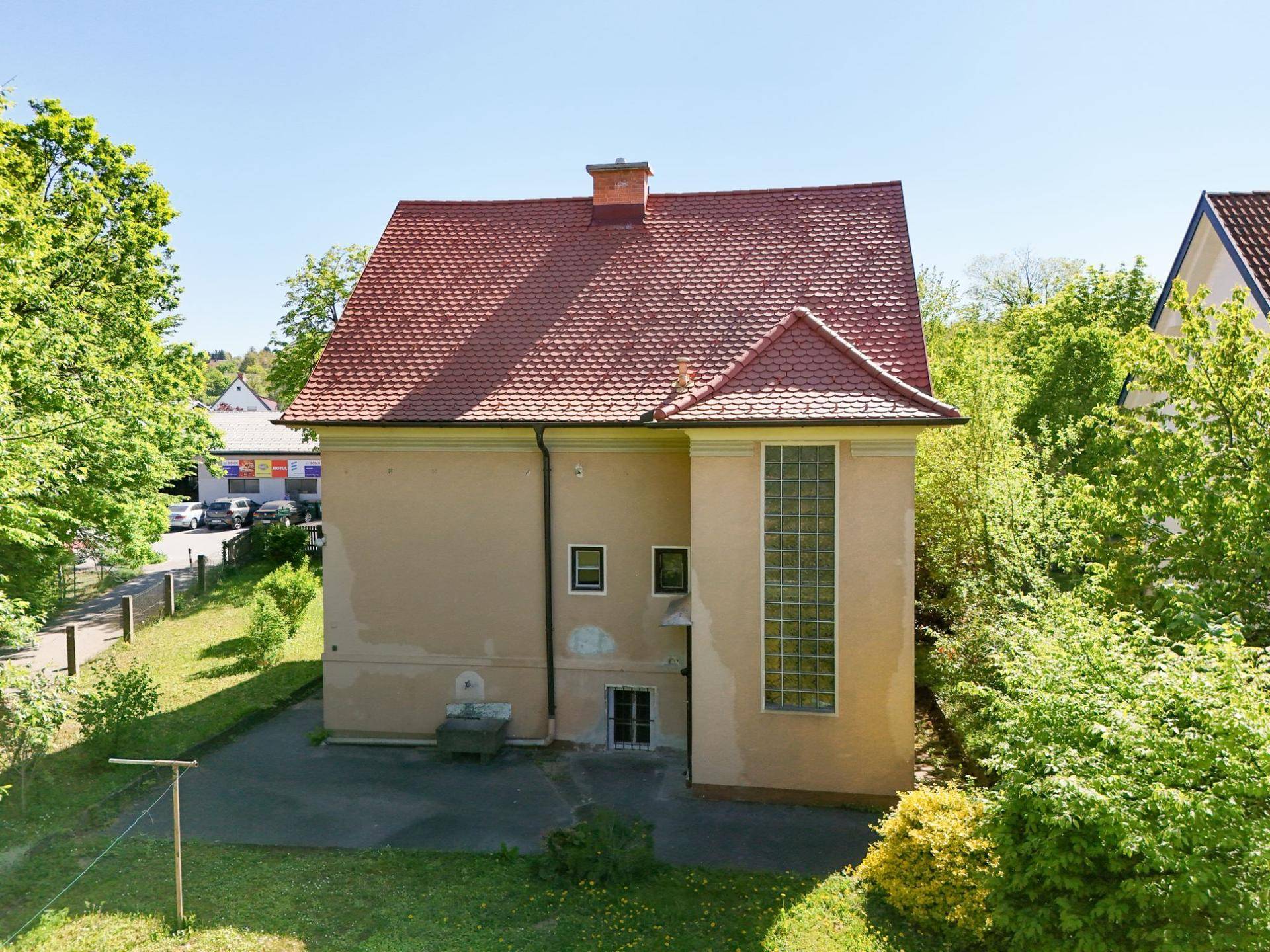 Rückansicht des Hauses mit großem Fenster und umgebendem Grün.