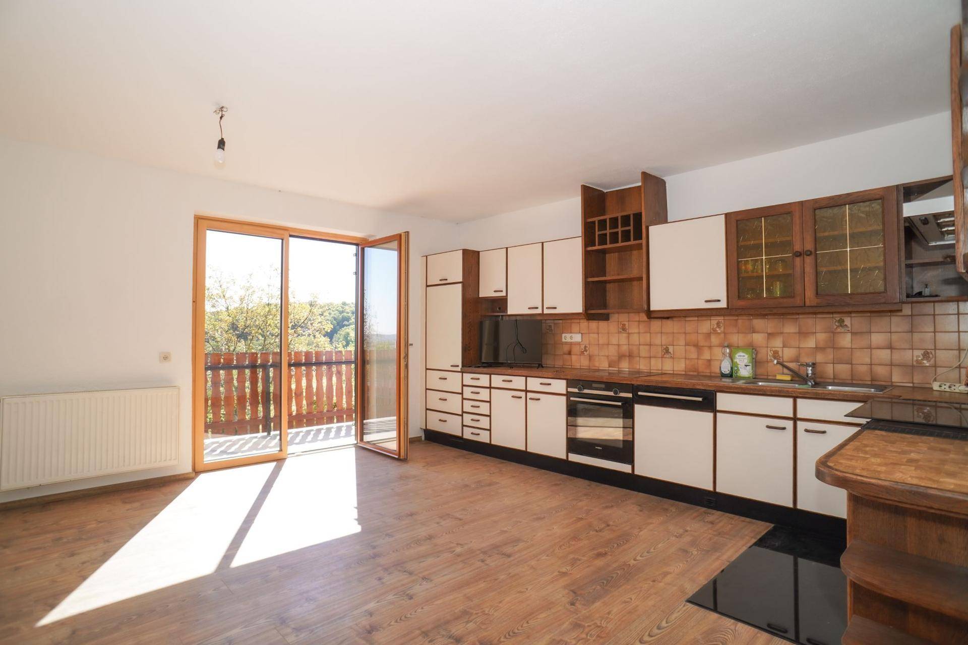 Geräumige Küche mit Holzboden, Einbauküche und direktem Zugang zum Balkon.