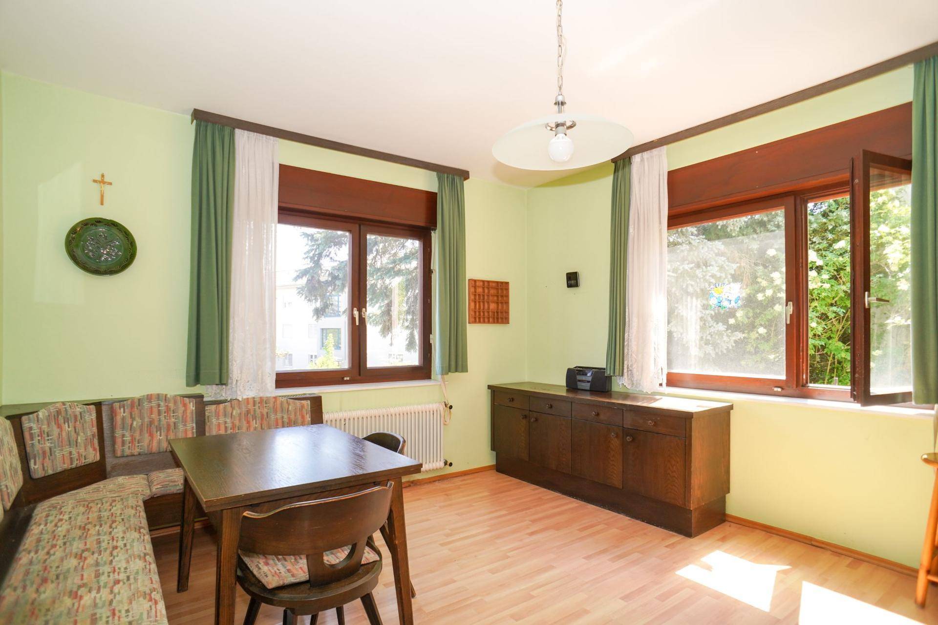 Gemütlicher Essbereich mit Eckbank, Holztisch und Blick ins Grüne durch große Fenster.