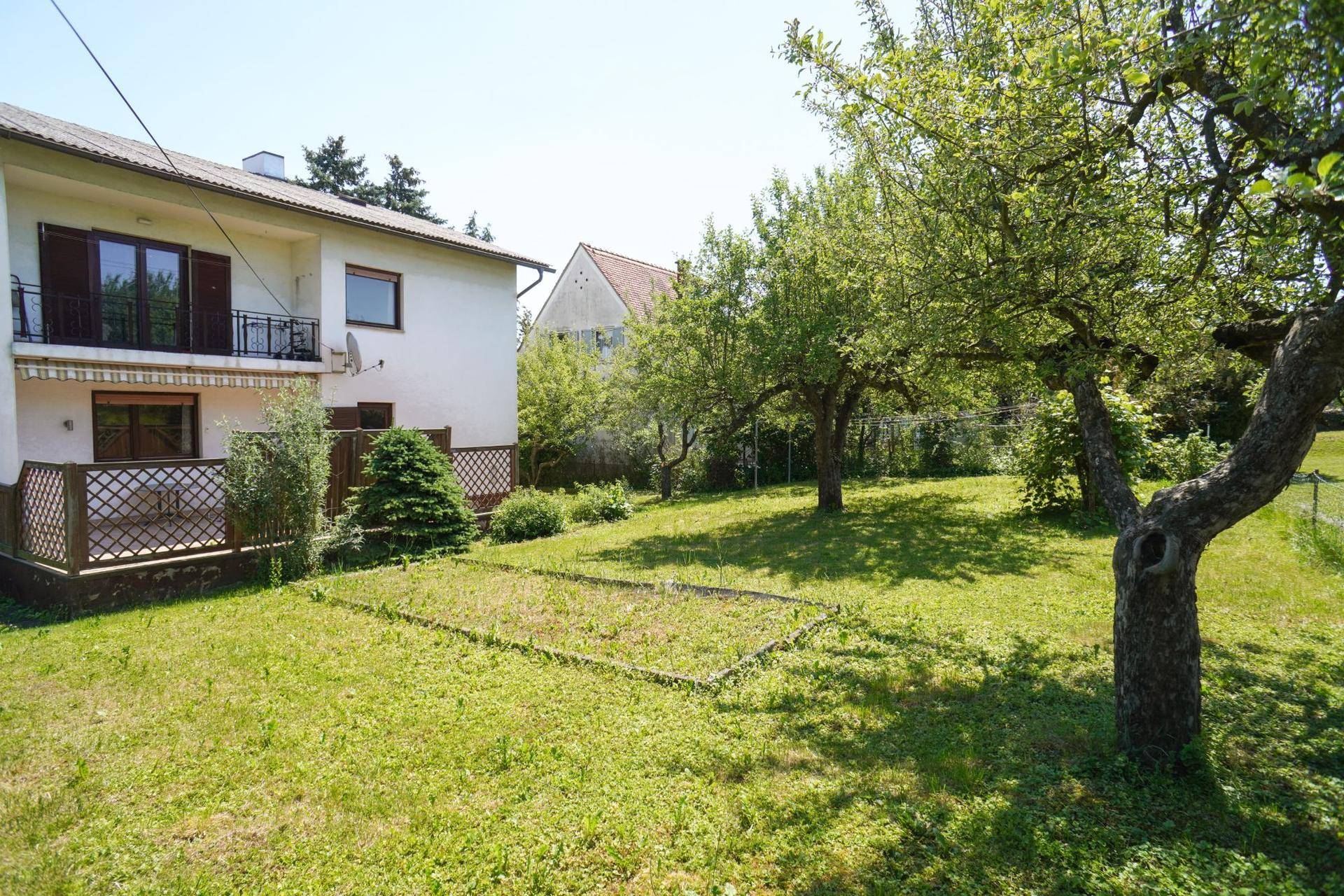 Weitläufiger Gartenbereich hinter dem Haus mit Obstbäumen und viel Grünfläche.