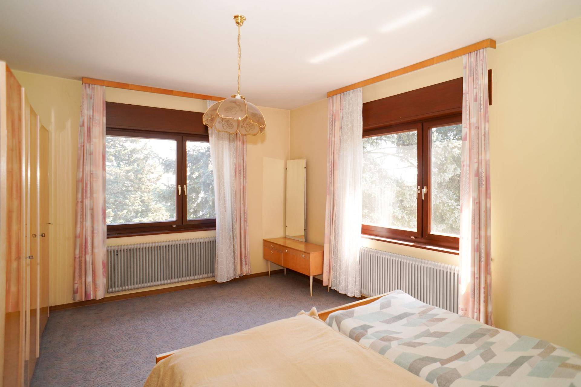 Helles Schlafzimmer mit zwei Einzelbetten, Teppichboden und Blick ins Grüne.
